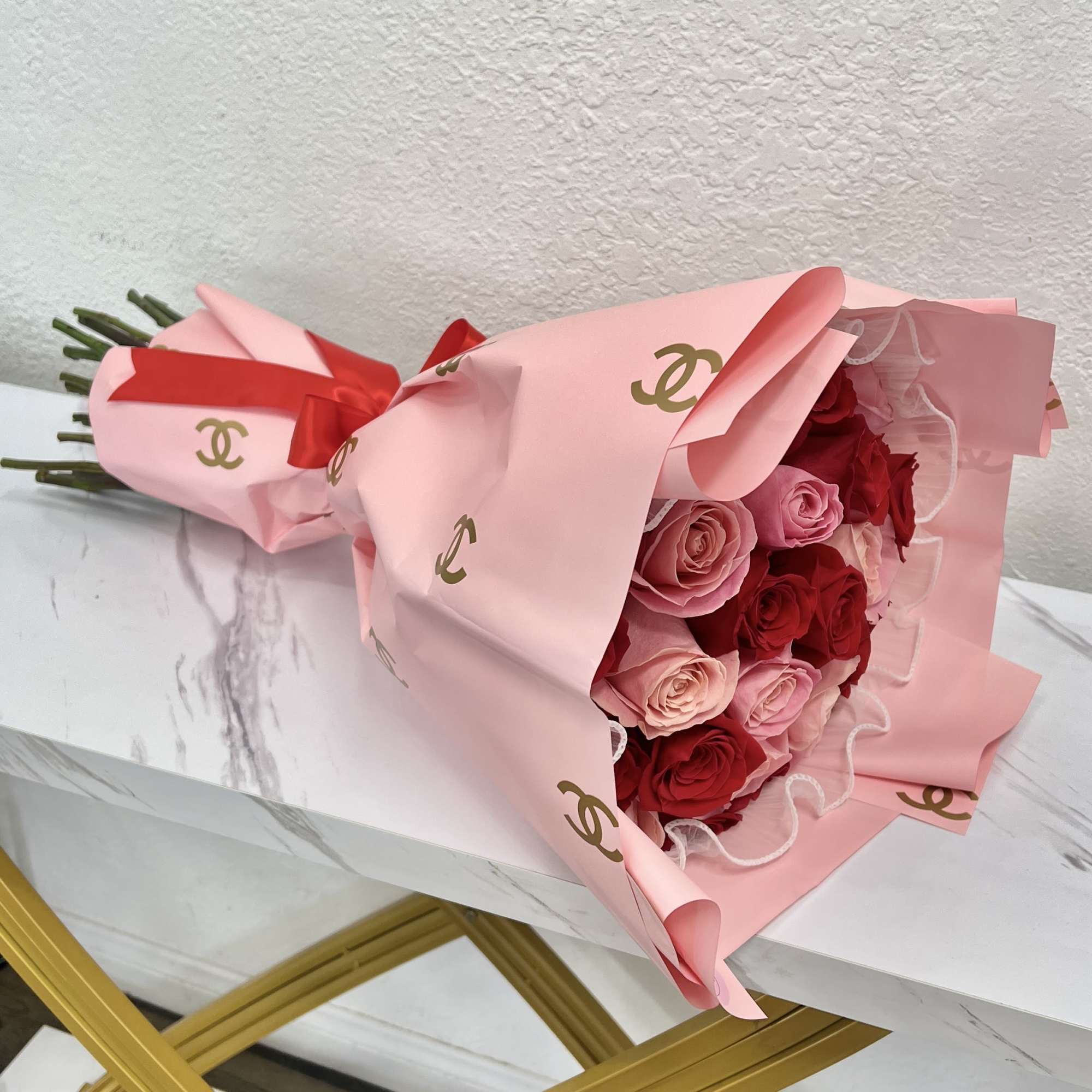 Pink and red rose bouquet wrapped in pink paper with ribbon