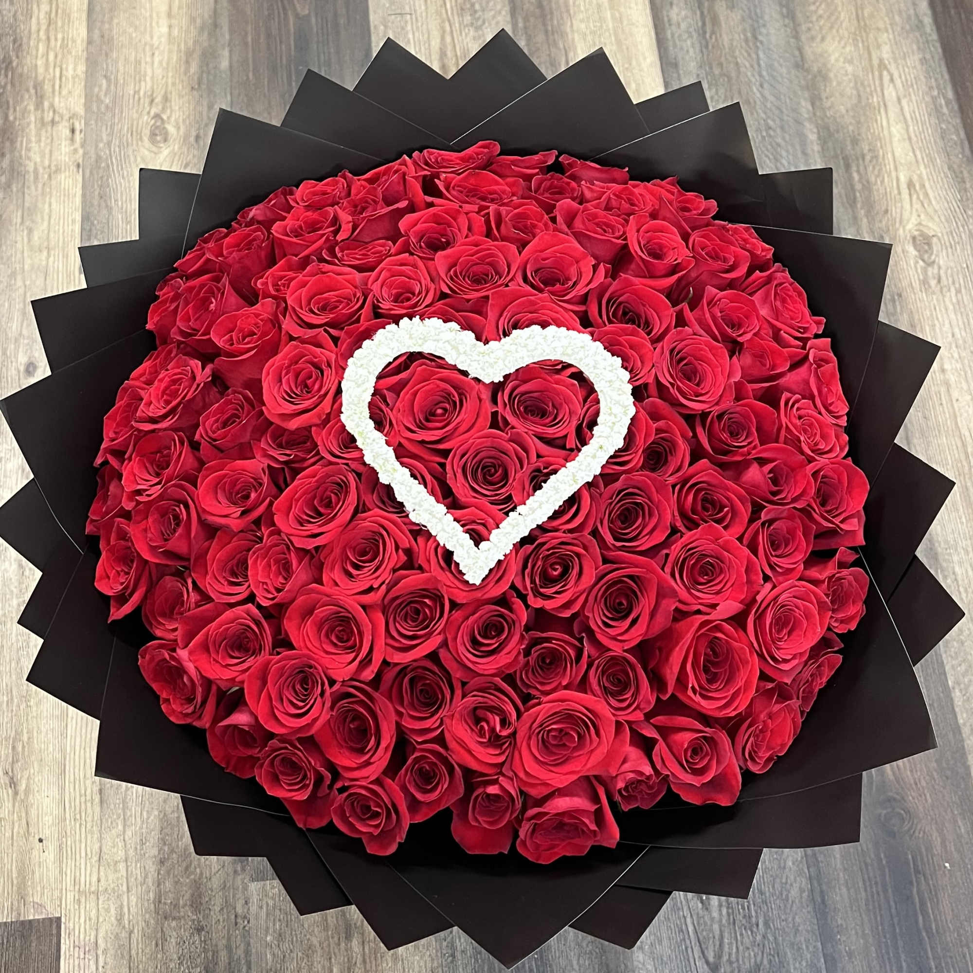 Round bouquet of red roses with a white heart accent