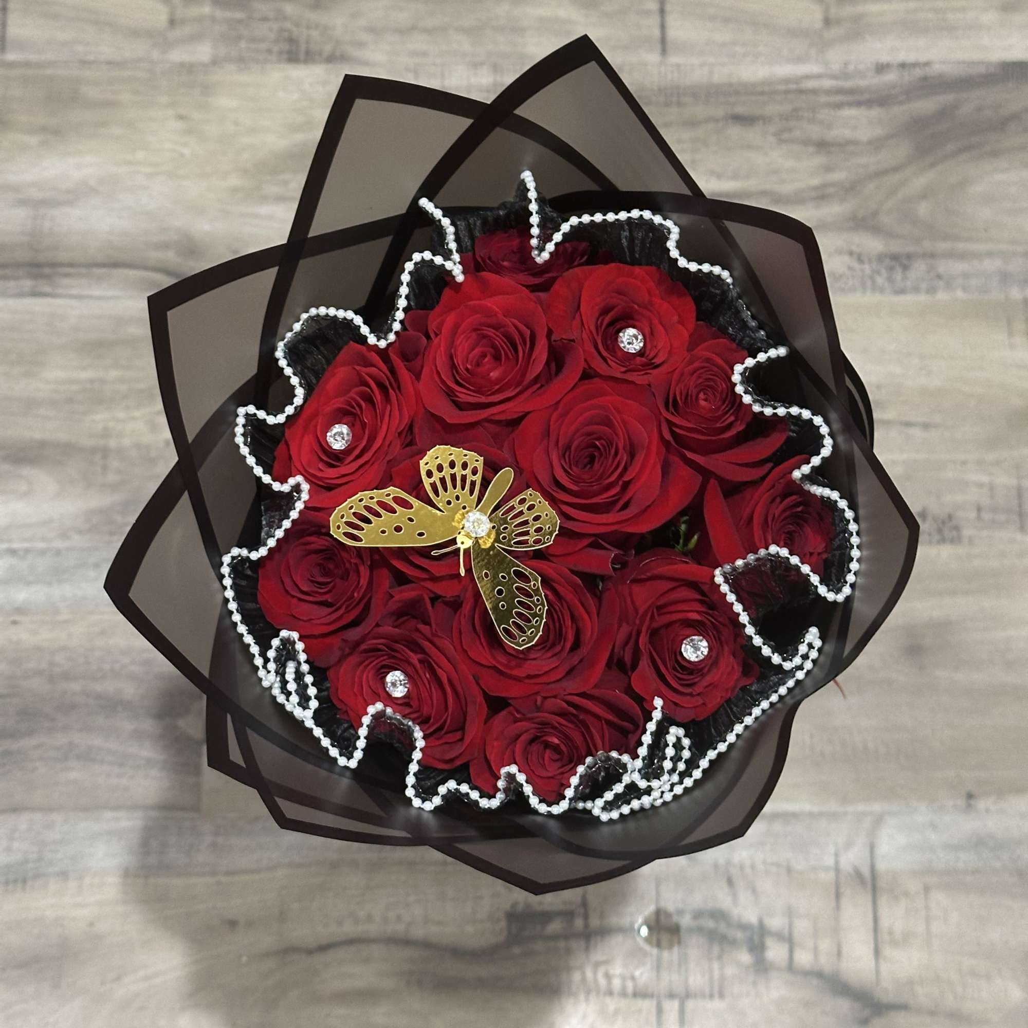 Bouquet of red roses wrapped in black paper with pearl trim
