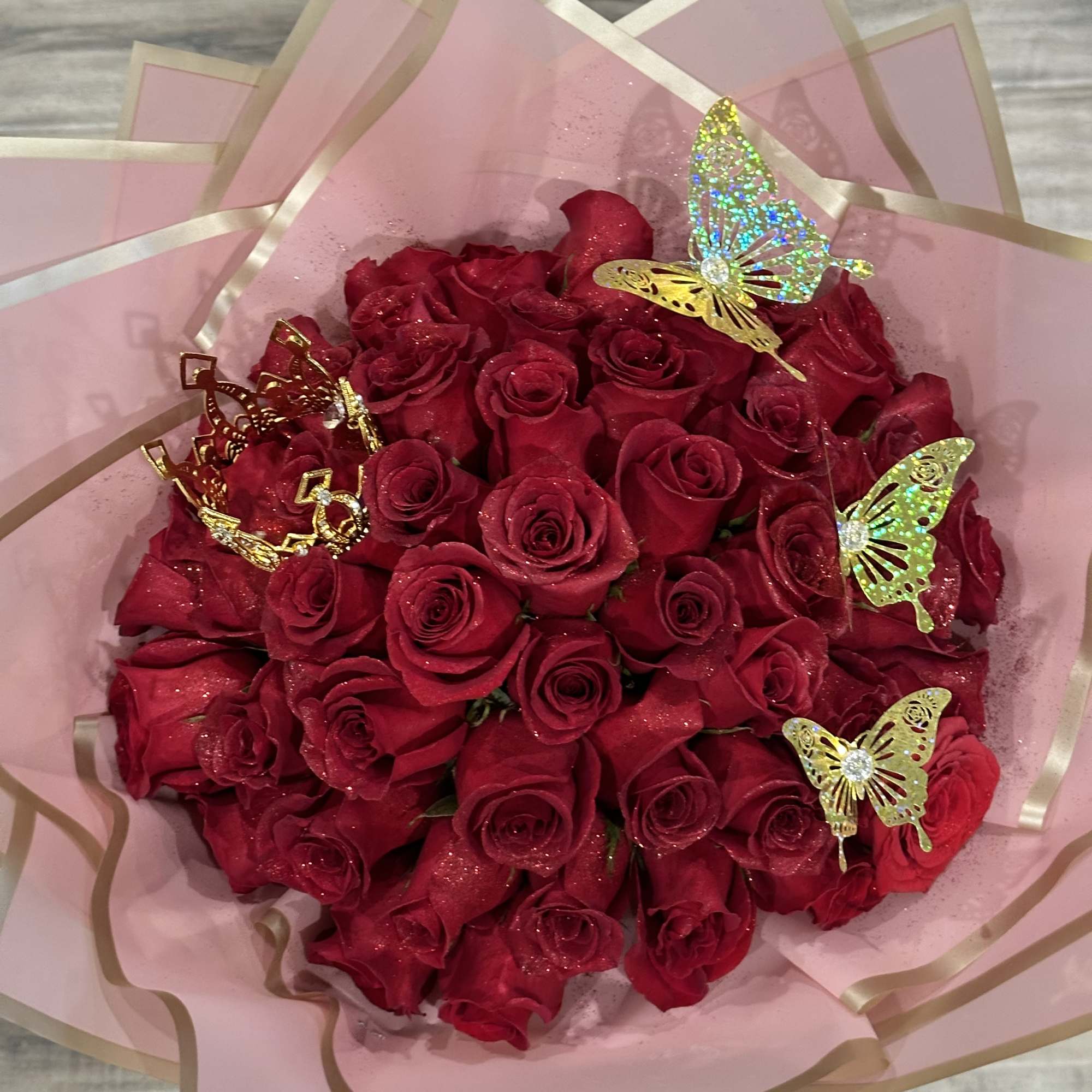 Bouquet of red roses wrapped in pink paper with butterfly picks