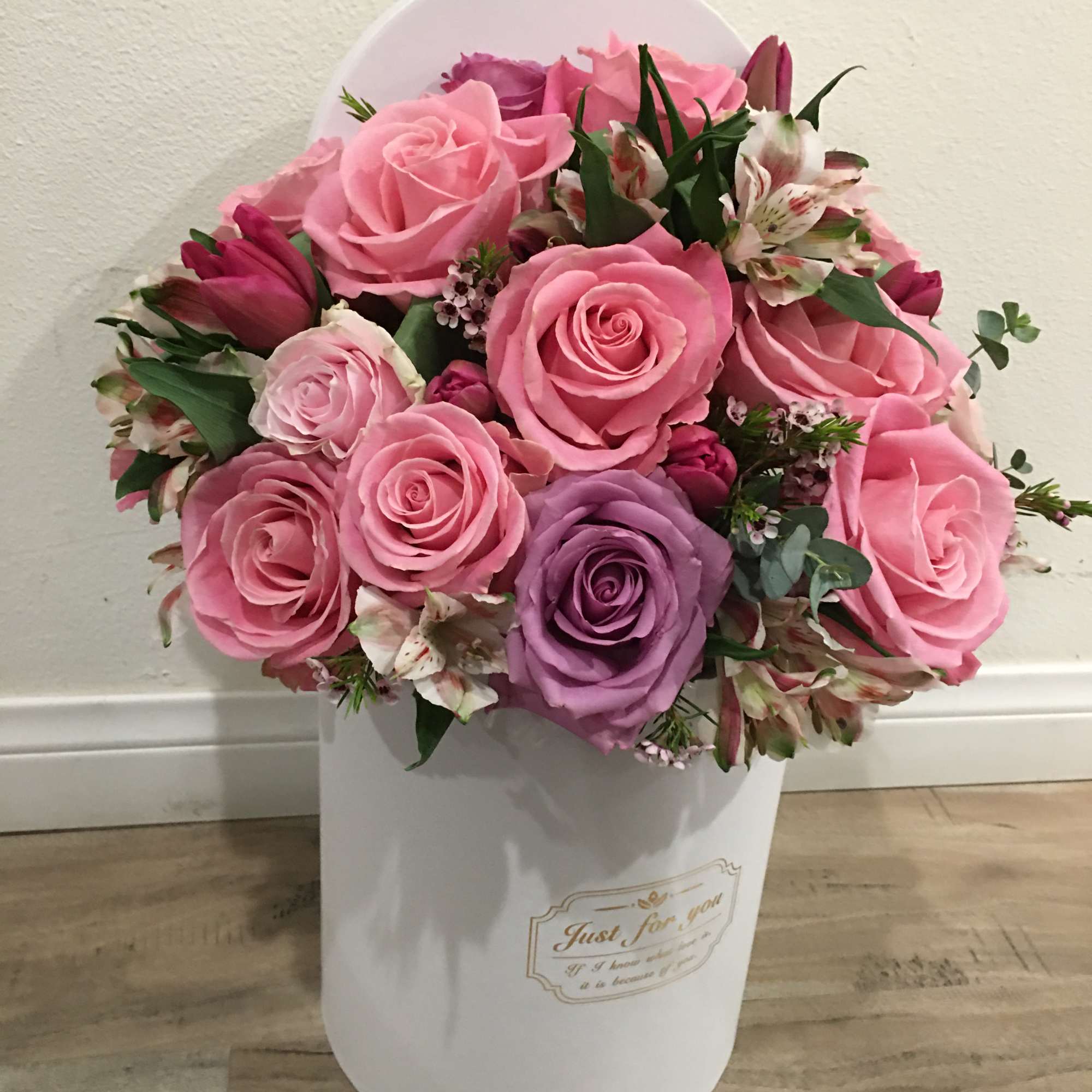 Pink and purple roses arranged in a white hatbox