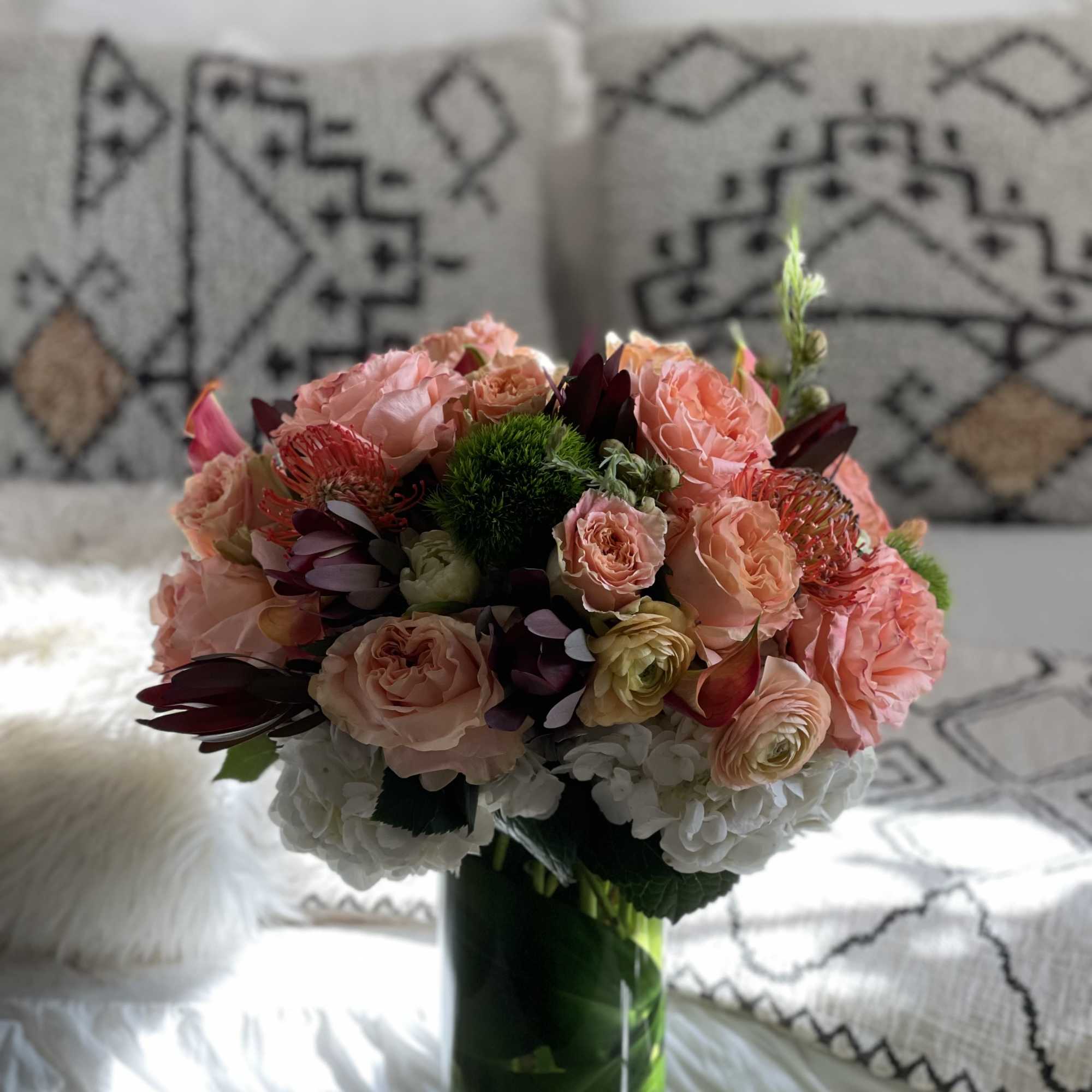 Pink and peach bouquet in a green glass vase