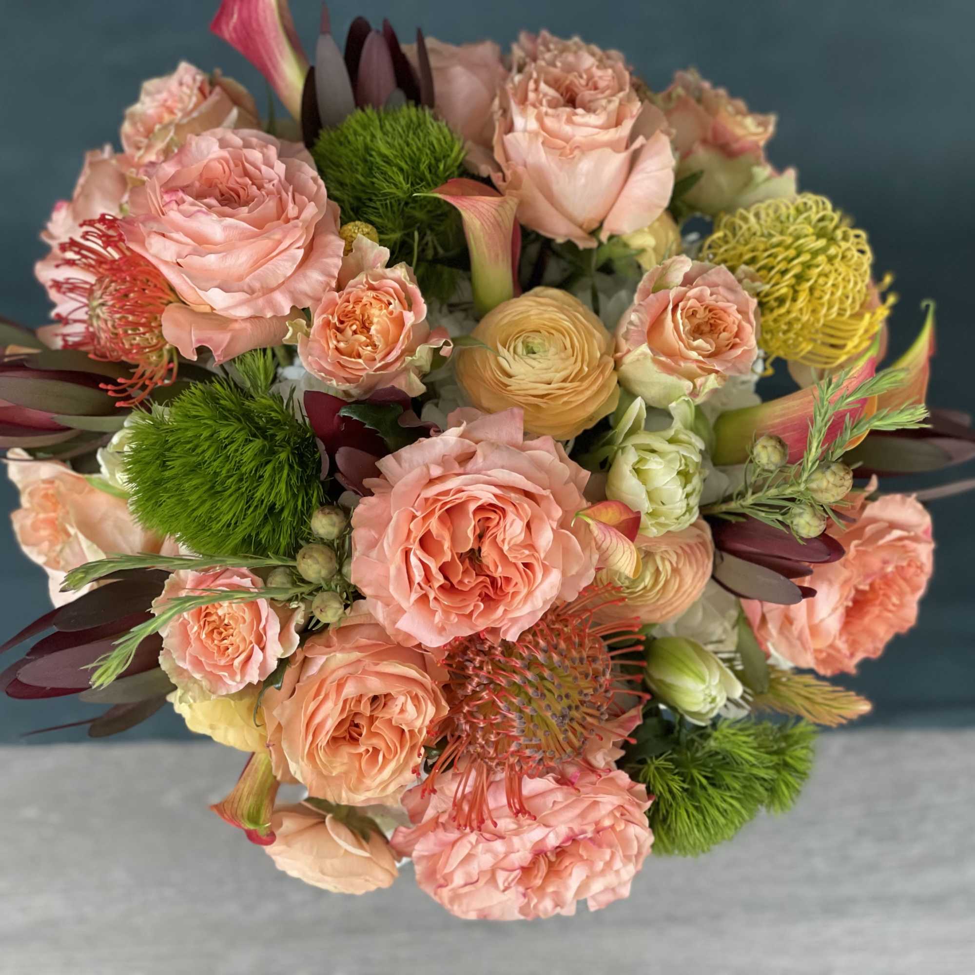 Bouquet of peach and pink roses with green accents