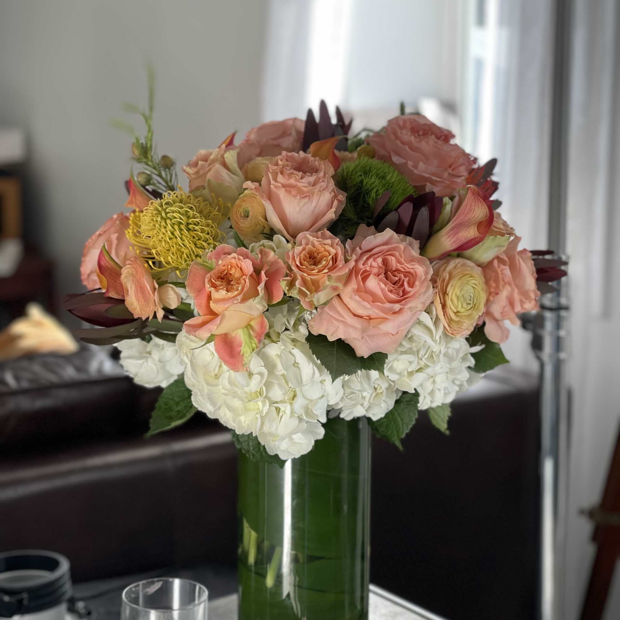 Peach roses and white hydrangeas in a tall glass vase
