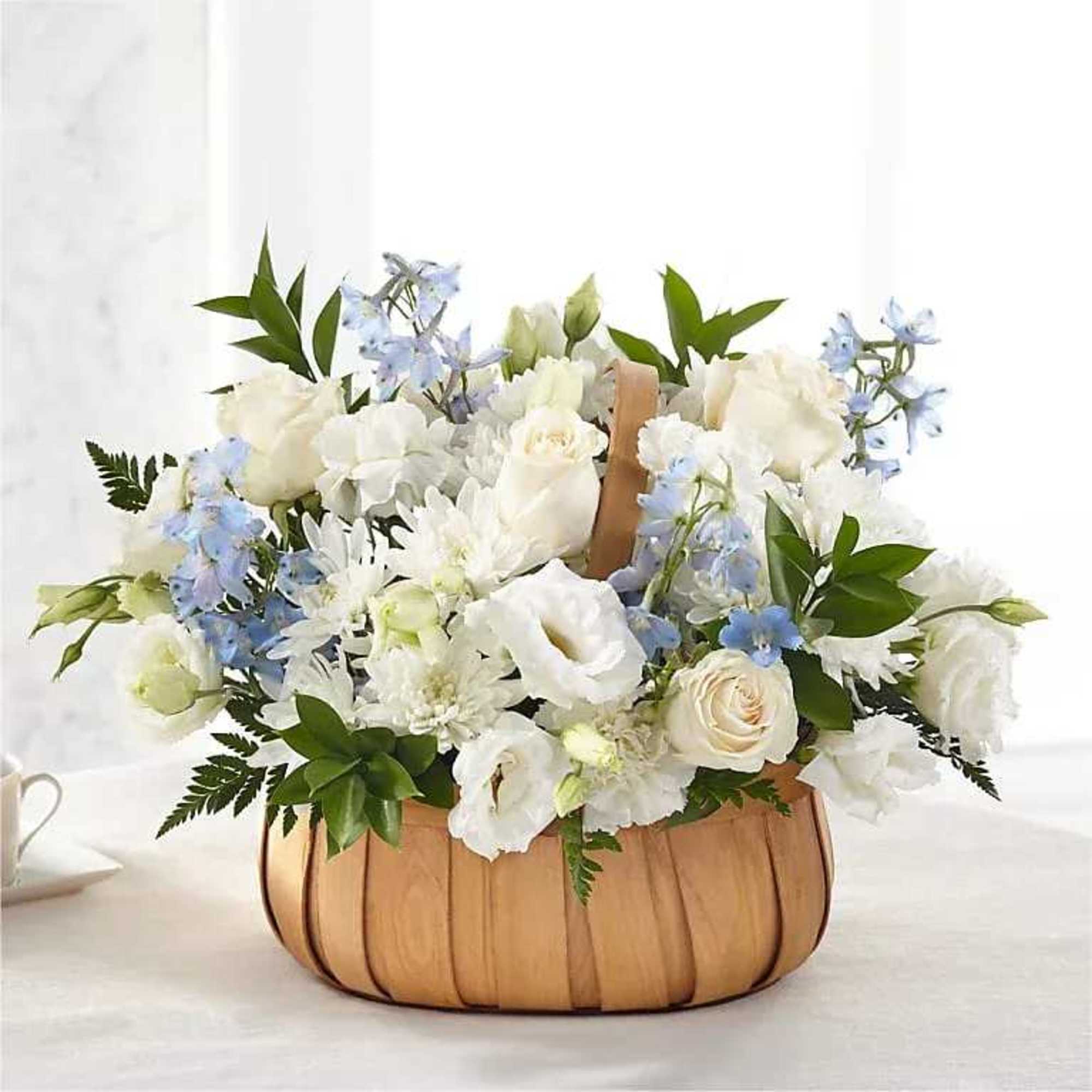 White and pale blue flower arrangement in a wooden basket
