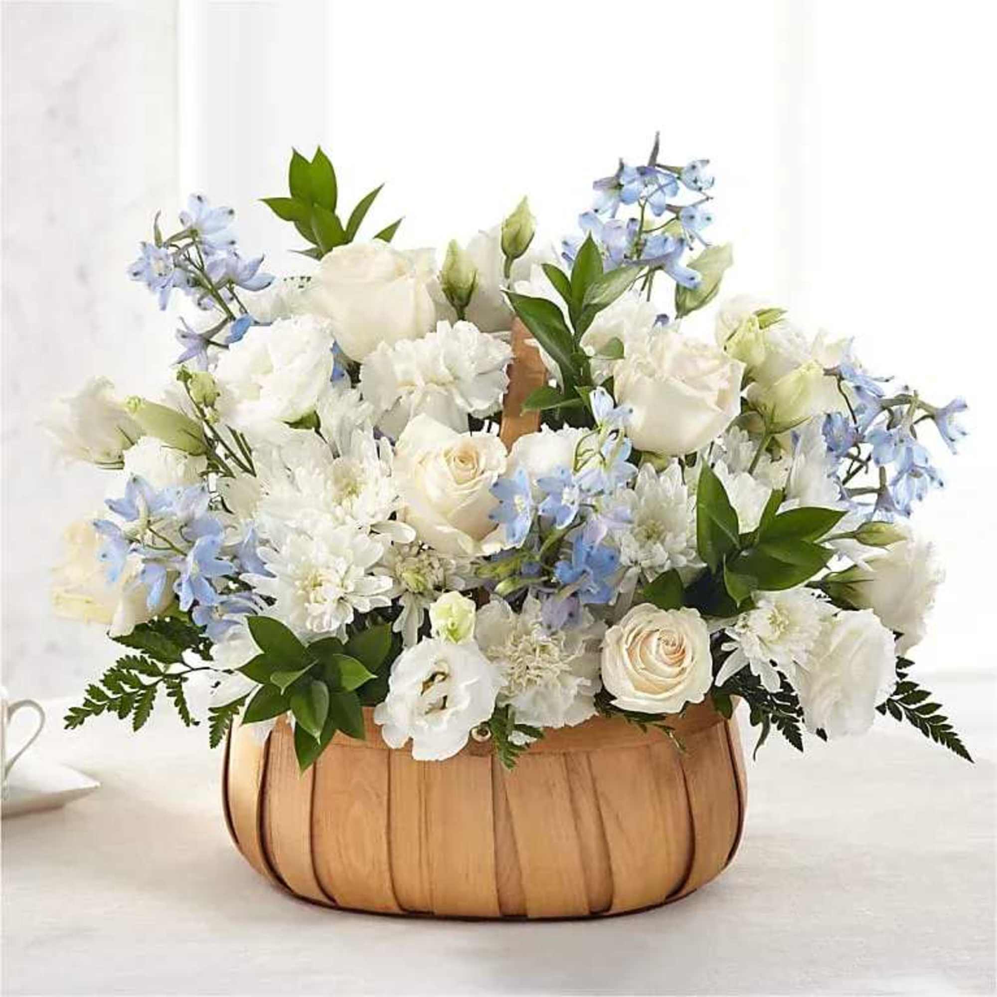 White and pale blue flower arrangement in a woven basket