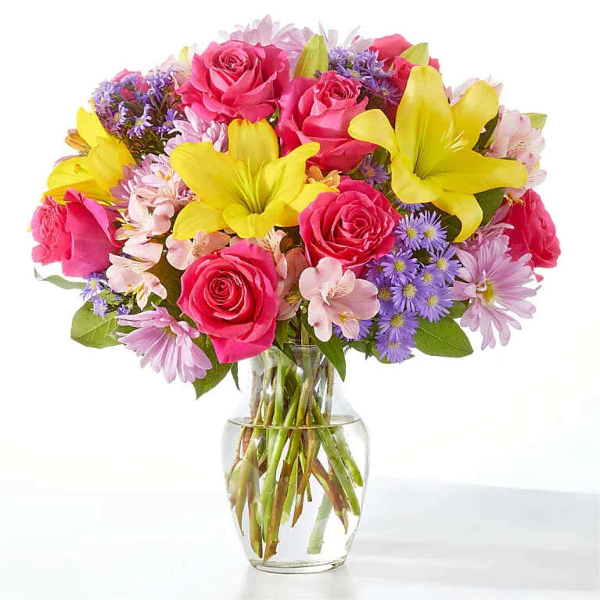Bouquet of pink roses and yellow lilies in a clear glass vase