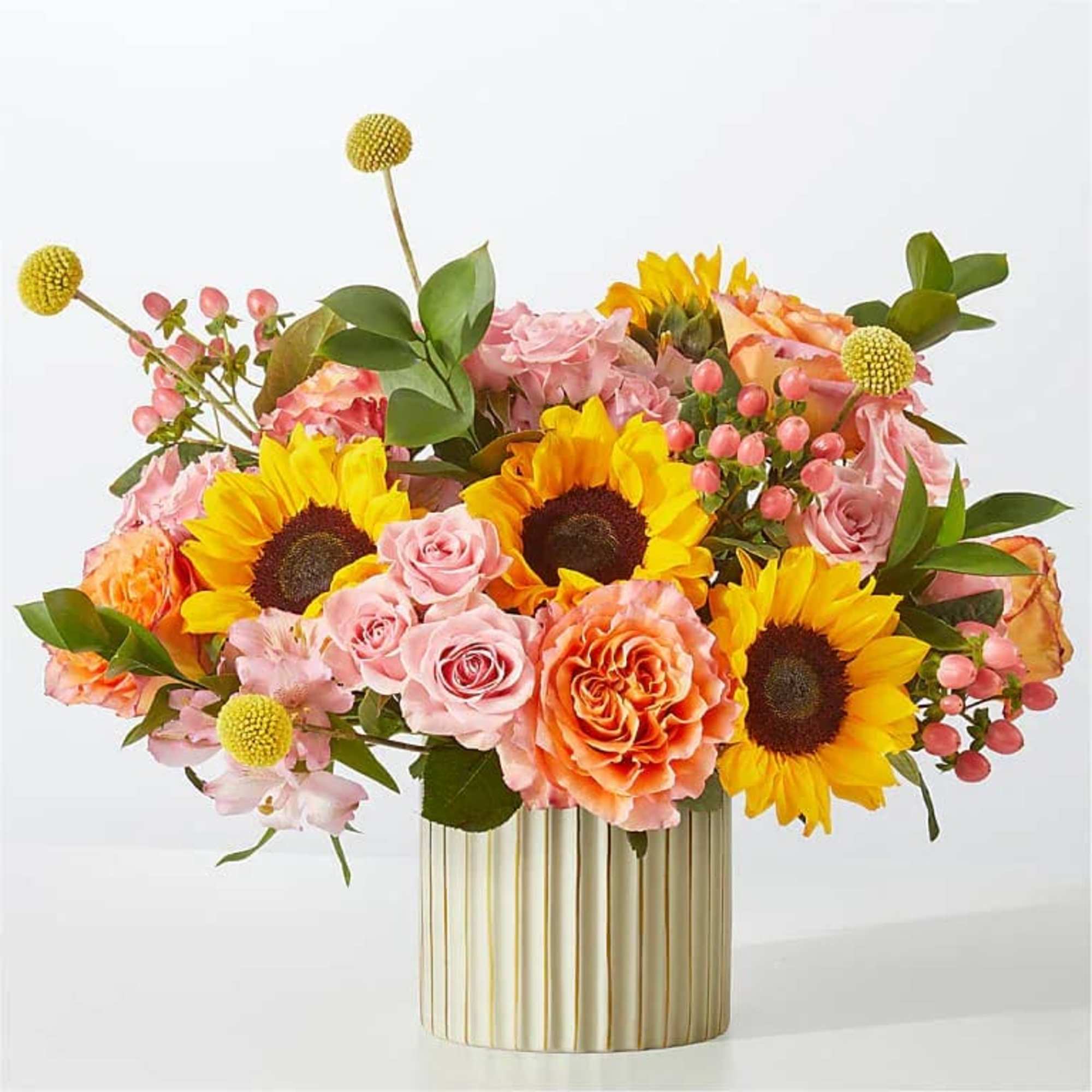 Bouquet of sunflowers, pink roses, and orange blooms in a gold vase