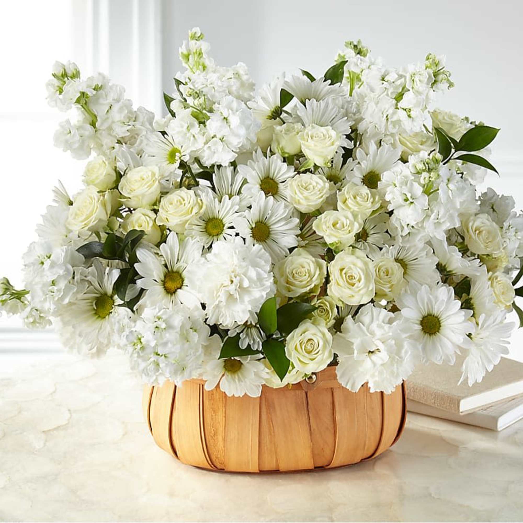 White roses and daisies arranged in a woven basket