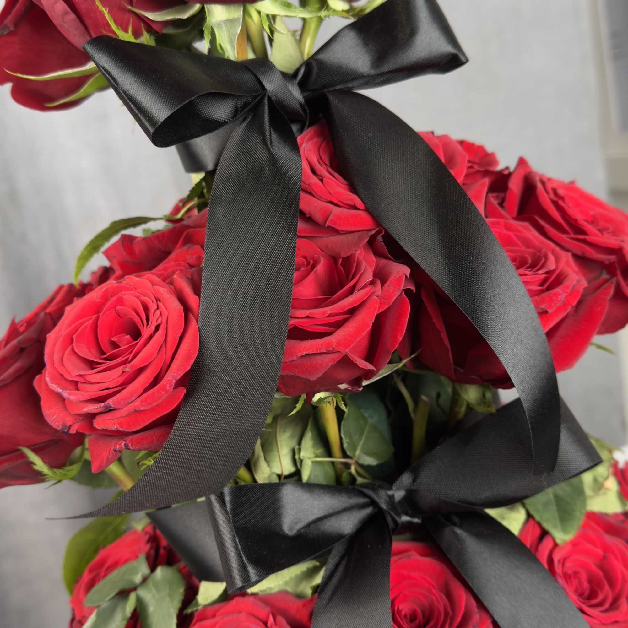 Stacked red roses tied with black ribbon