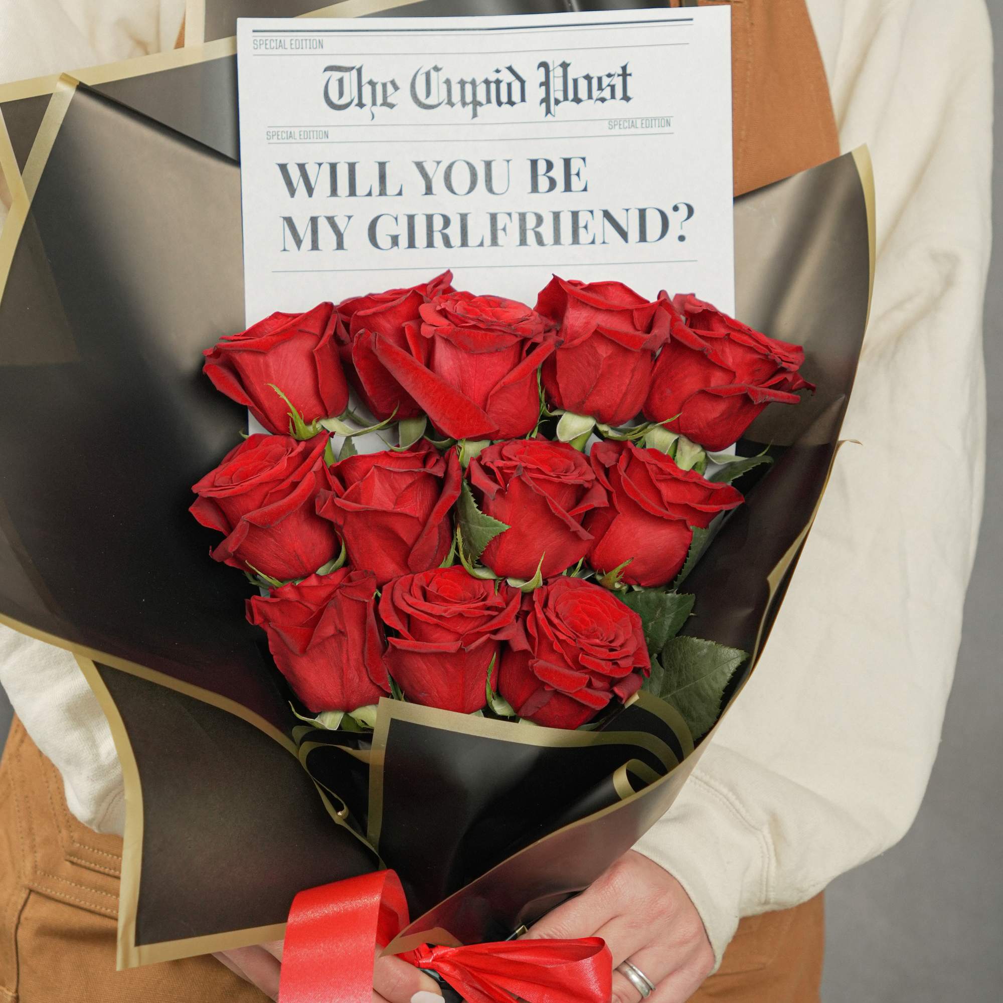 Bouquet of red roses wrapped in black paper with a proposal card
