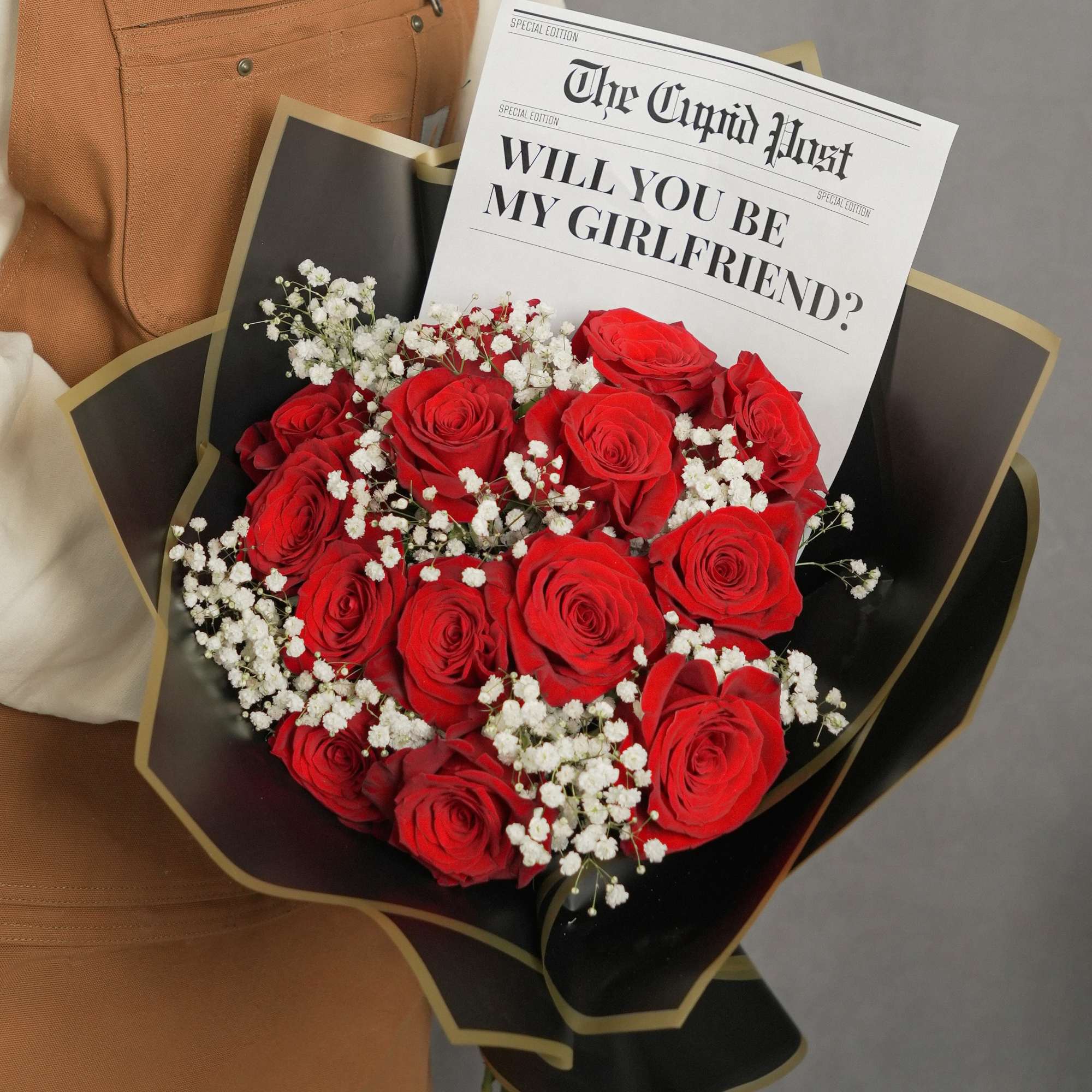 Bouquet of red roses with baby's breath and a newspaper-style card