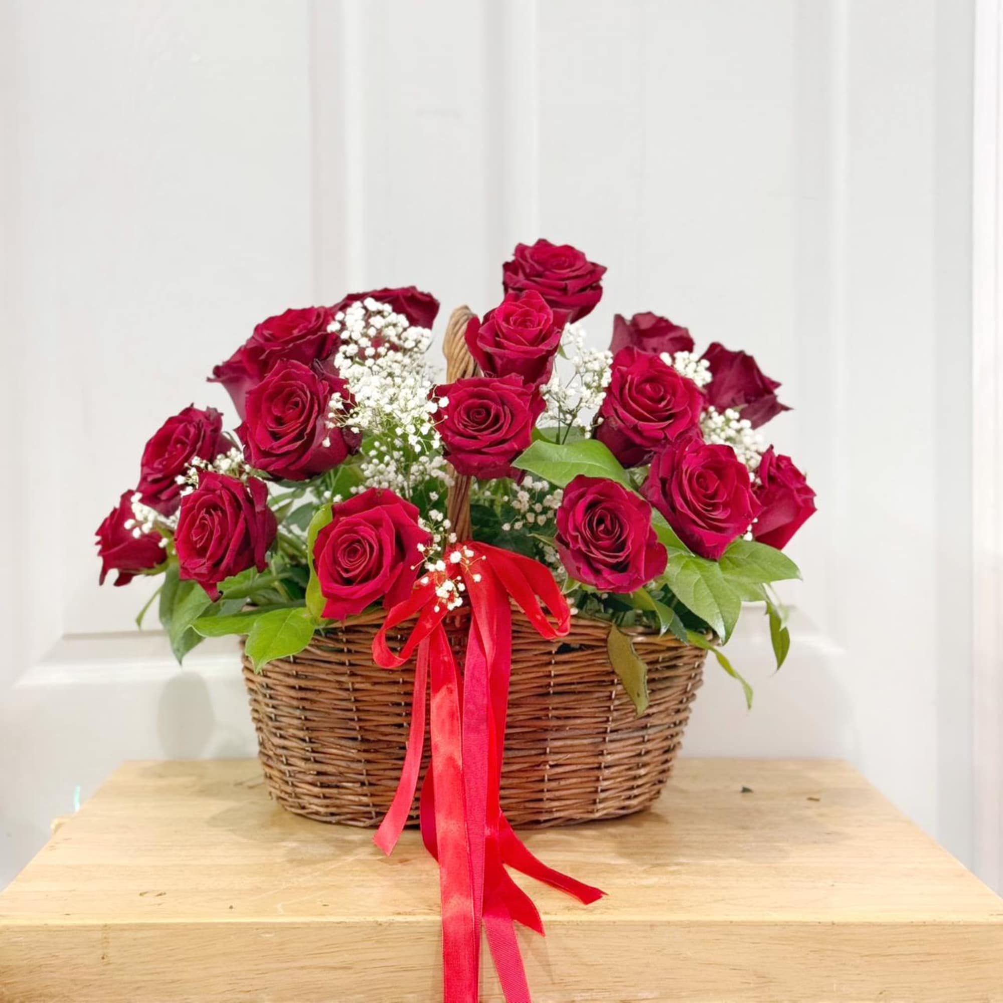 Basket of red roses with baby's breath and a red ribbon