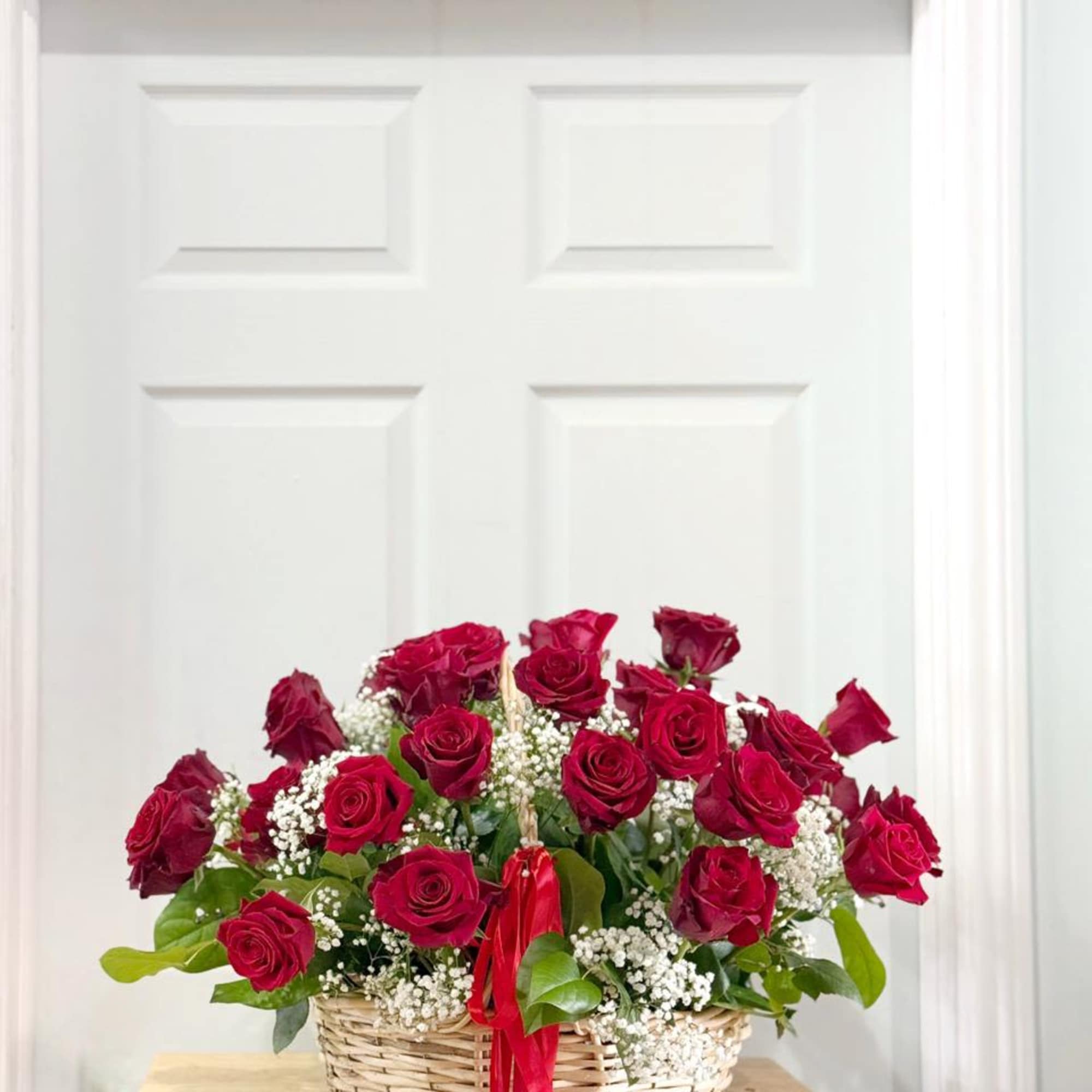 Basket of red roses with baby's breath and a red ribbon
