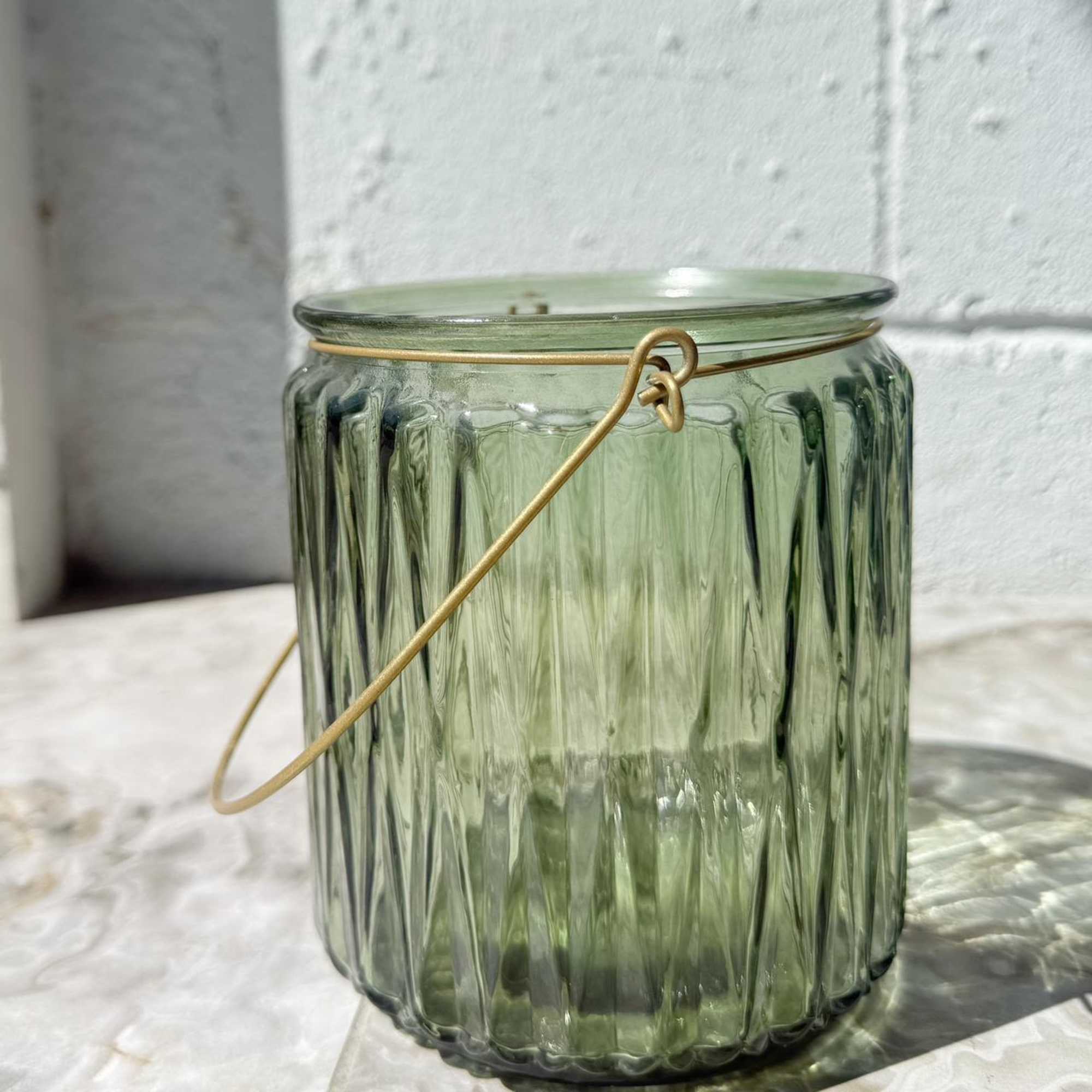 Green glass candle holder with a metal handle