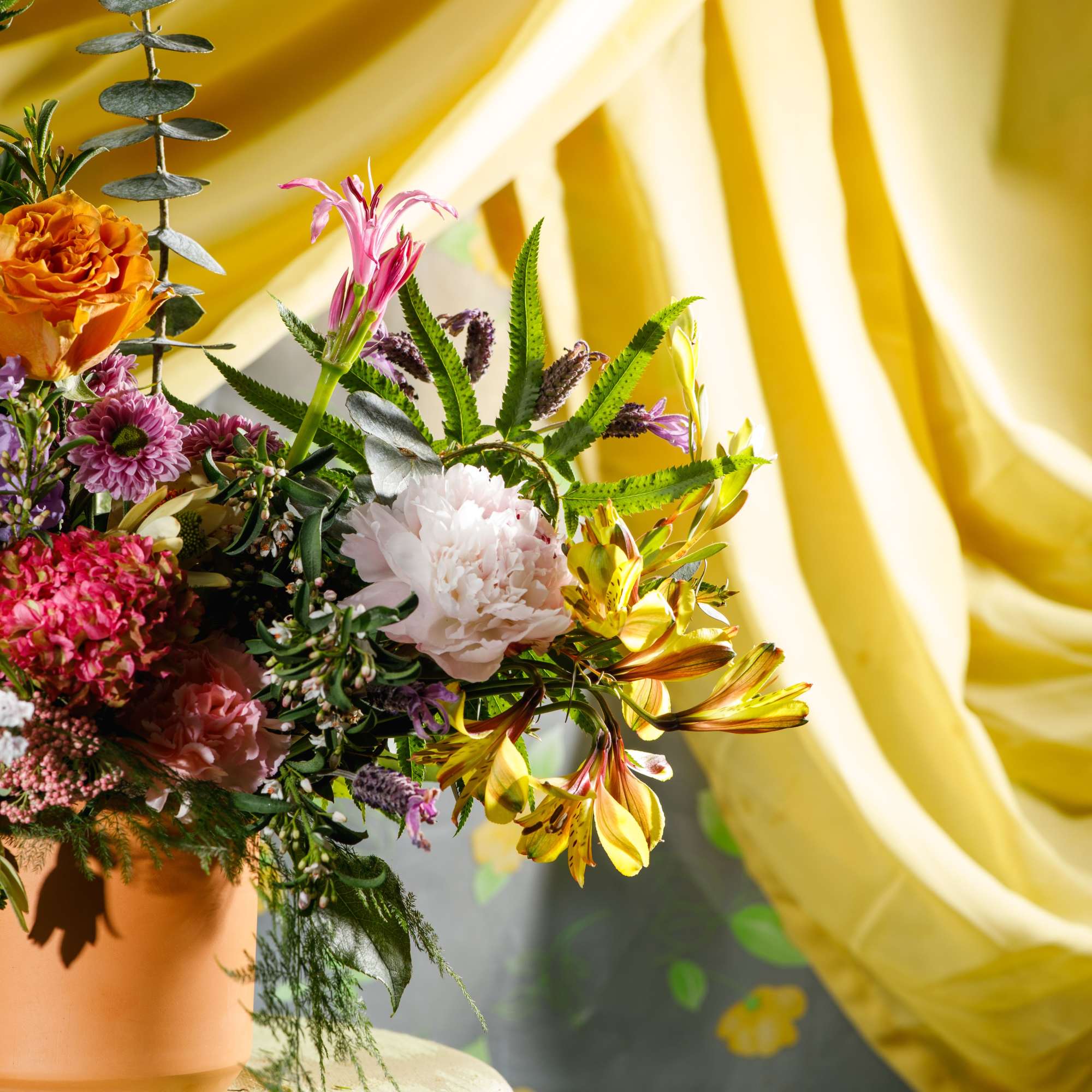 Colorful mixed arrangement with roses, peonies, hydrangea and alstroemeria in a terracotta pot