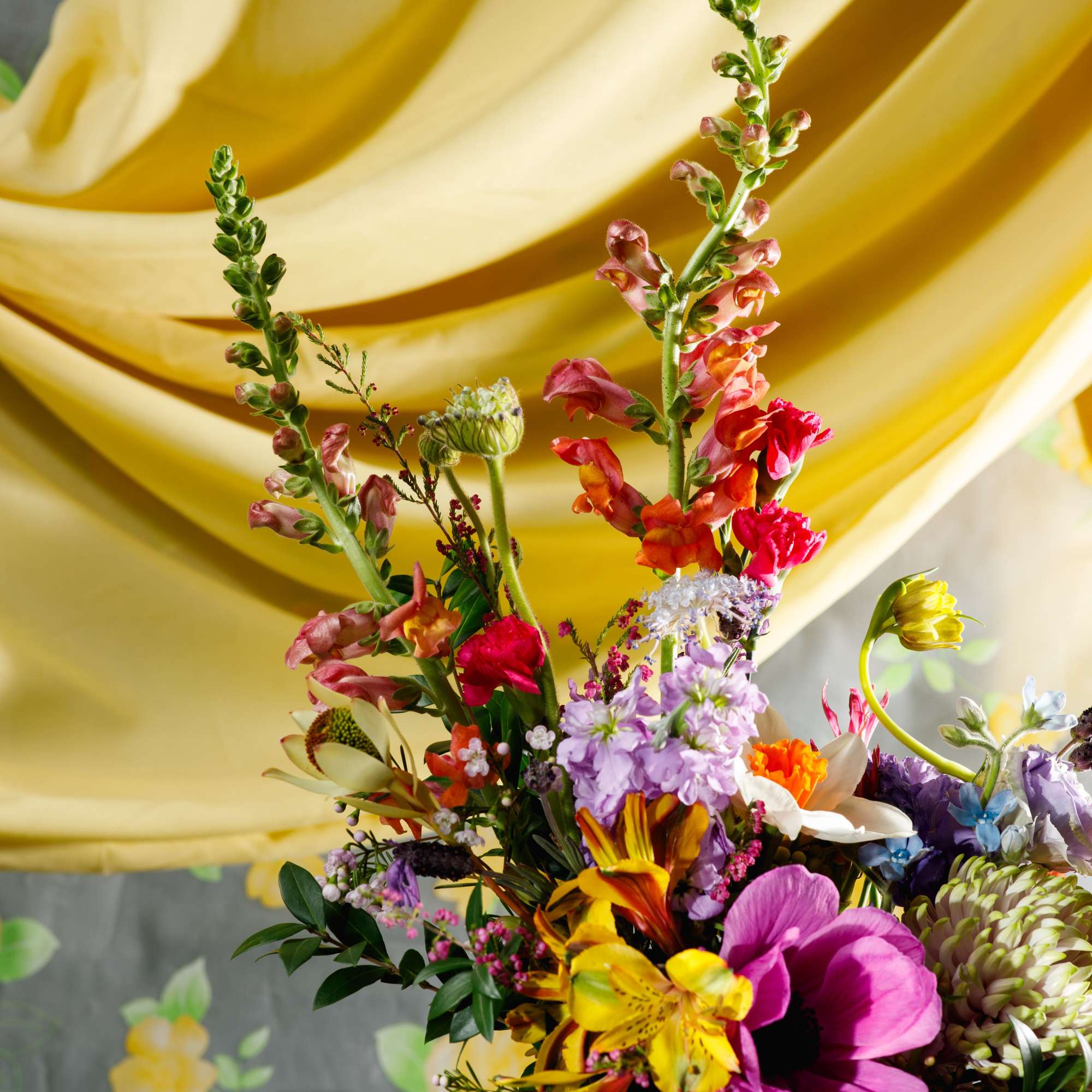 Tall mixed arrangement of colorful spring flowers in a simple white vase