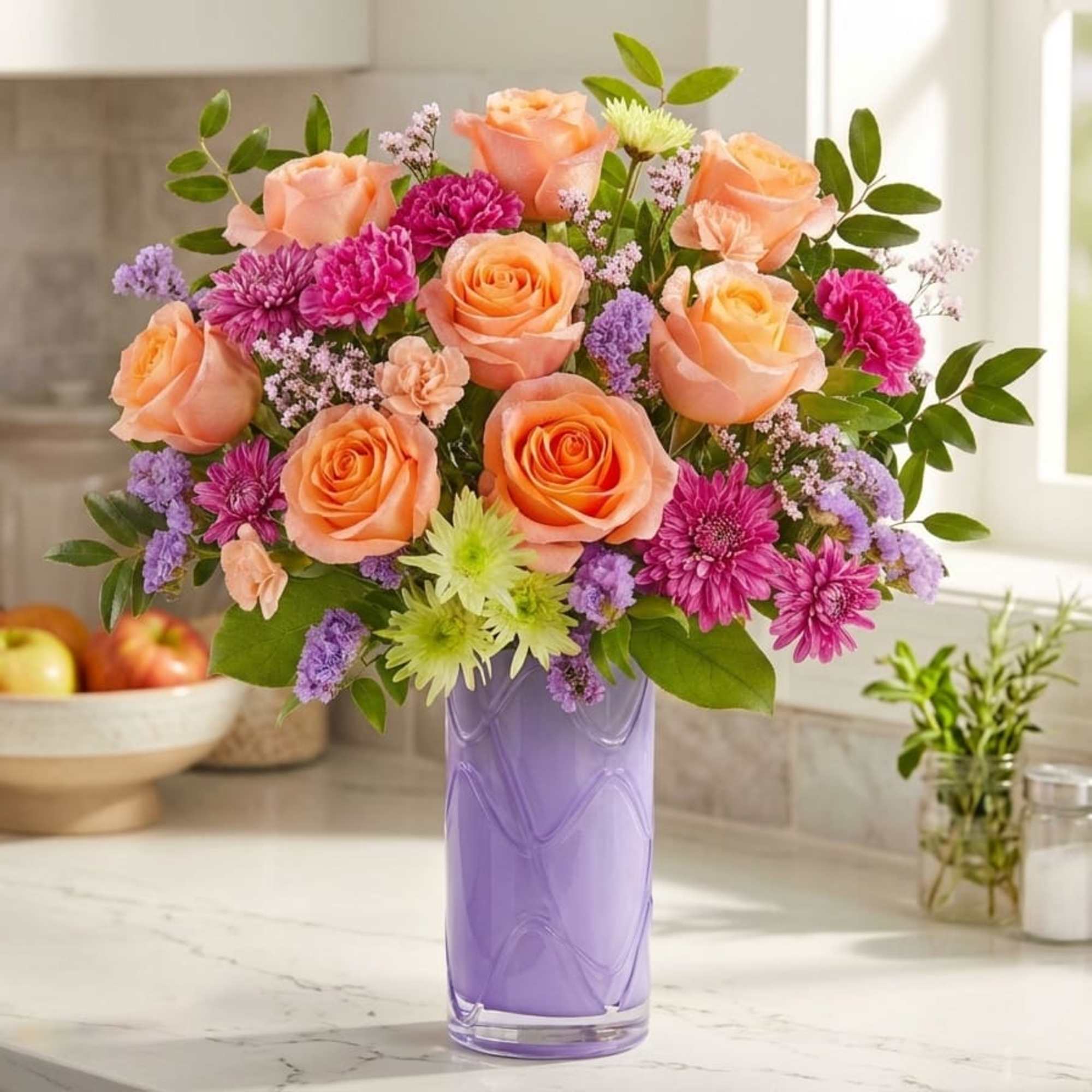Peach roses and purple flowers in a lavender glass vase