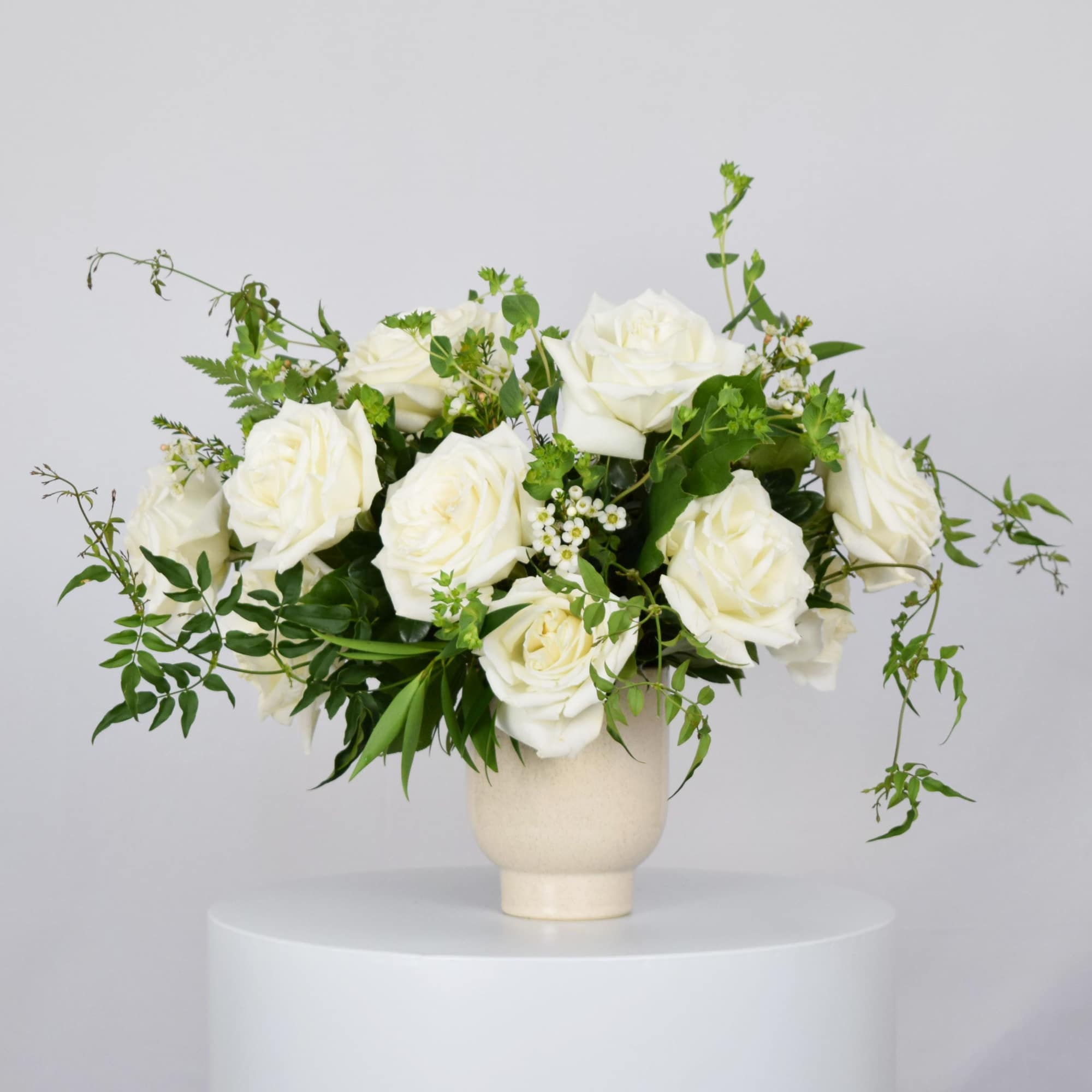 White rose arrangement in a cream vase