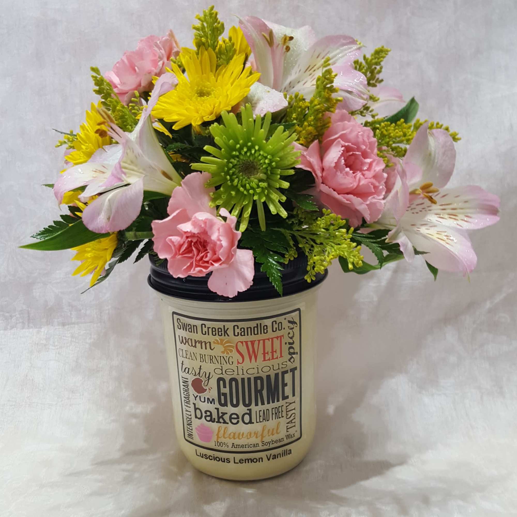 A cute, petite floral arrangement on top of a 12 oz. Swan