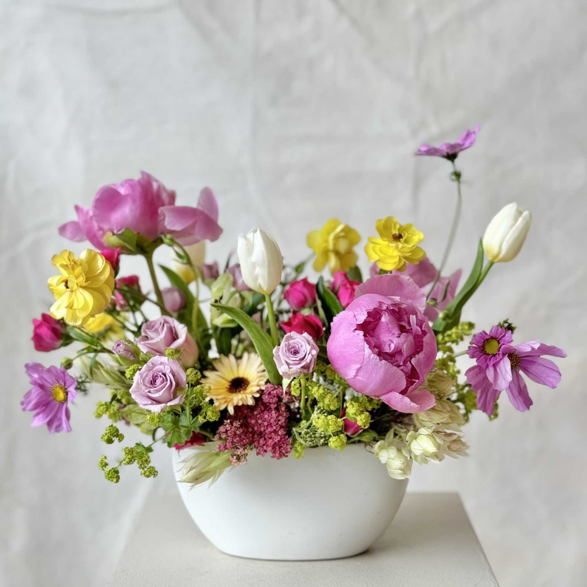 Mixed pink, yellow, and white flowers in a white bowl vase