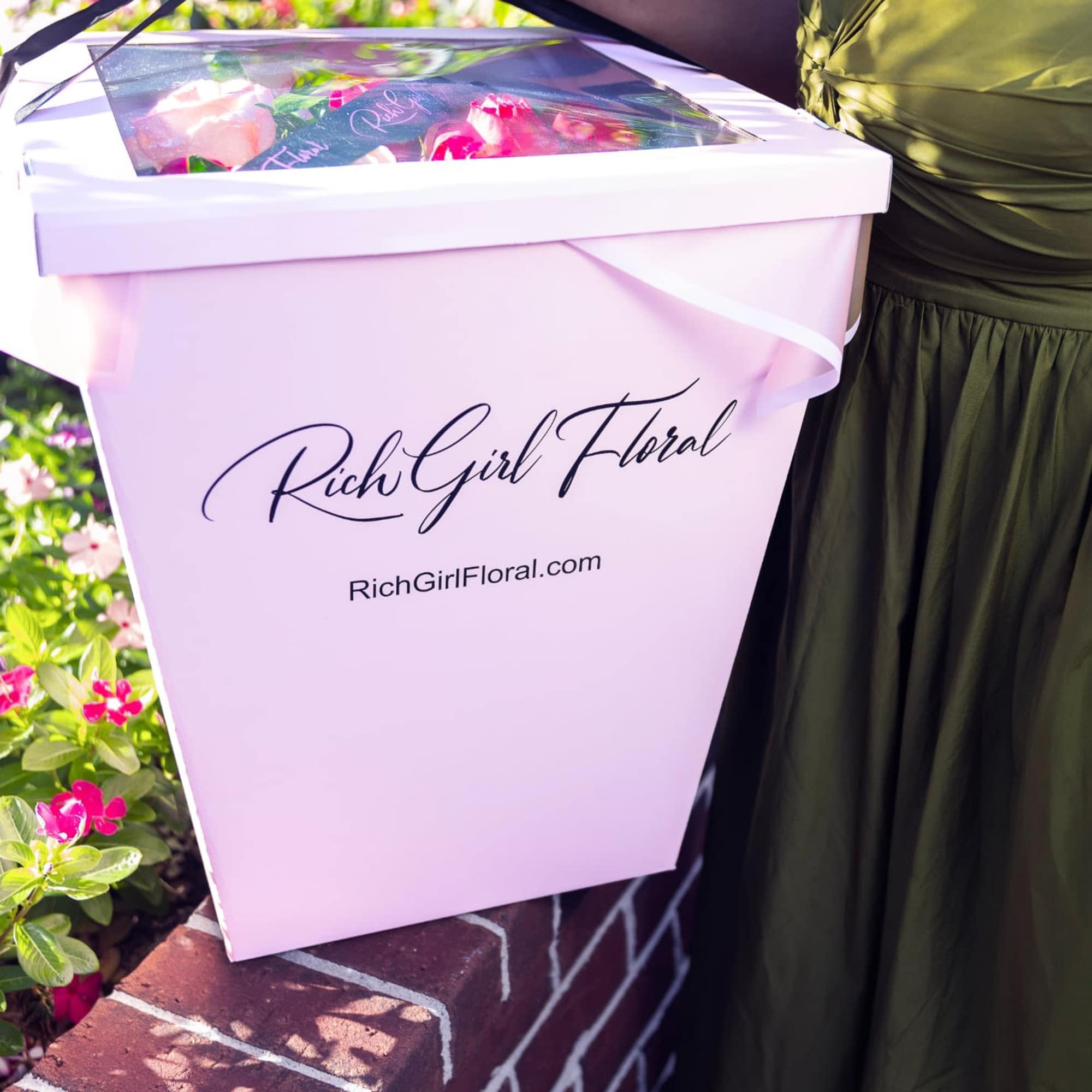 Pink floral gift box with a clear lid and black ribbon handle