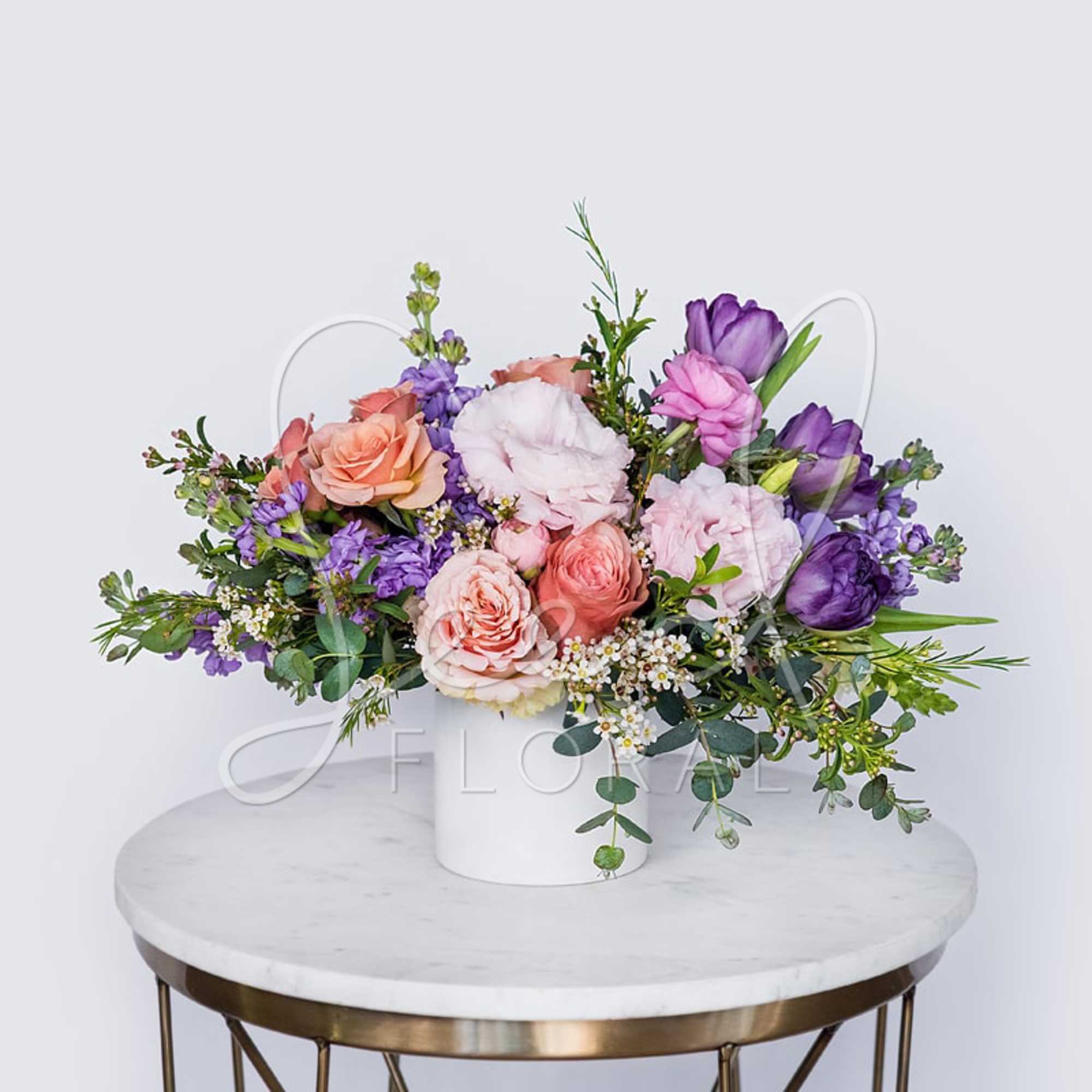 Pastel floral arrangement in a white vase with pink and purple blooms