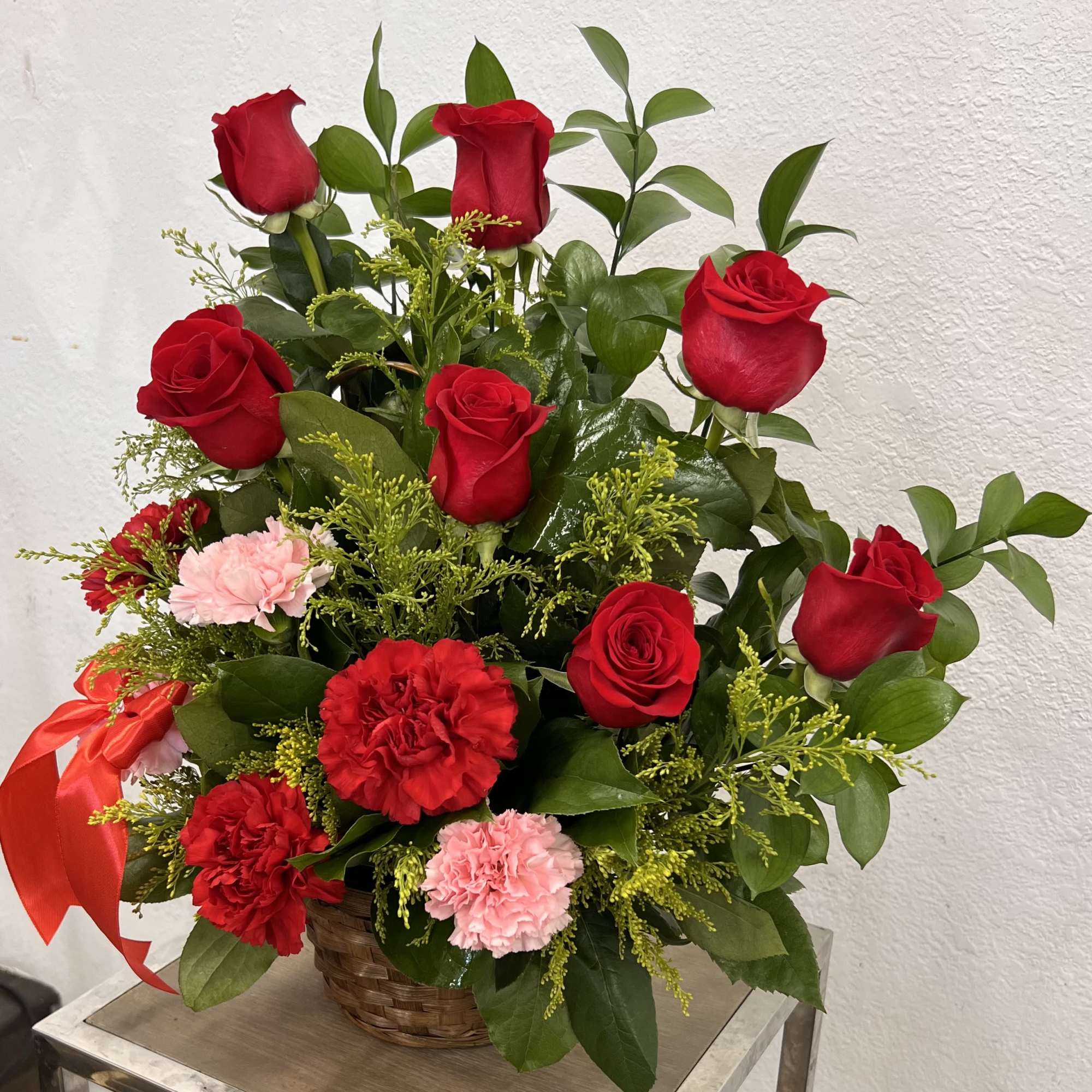 Basket arrangement of red roses and carnations with pink accents