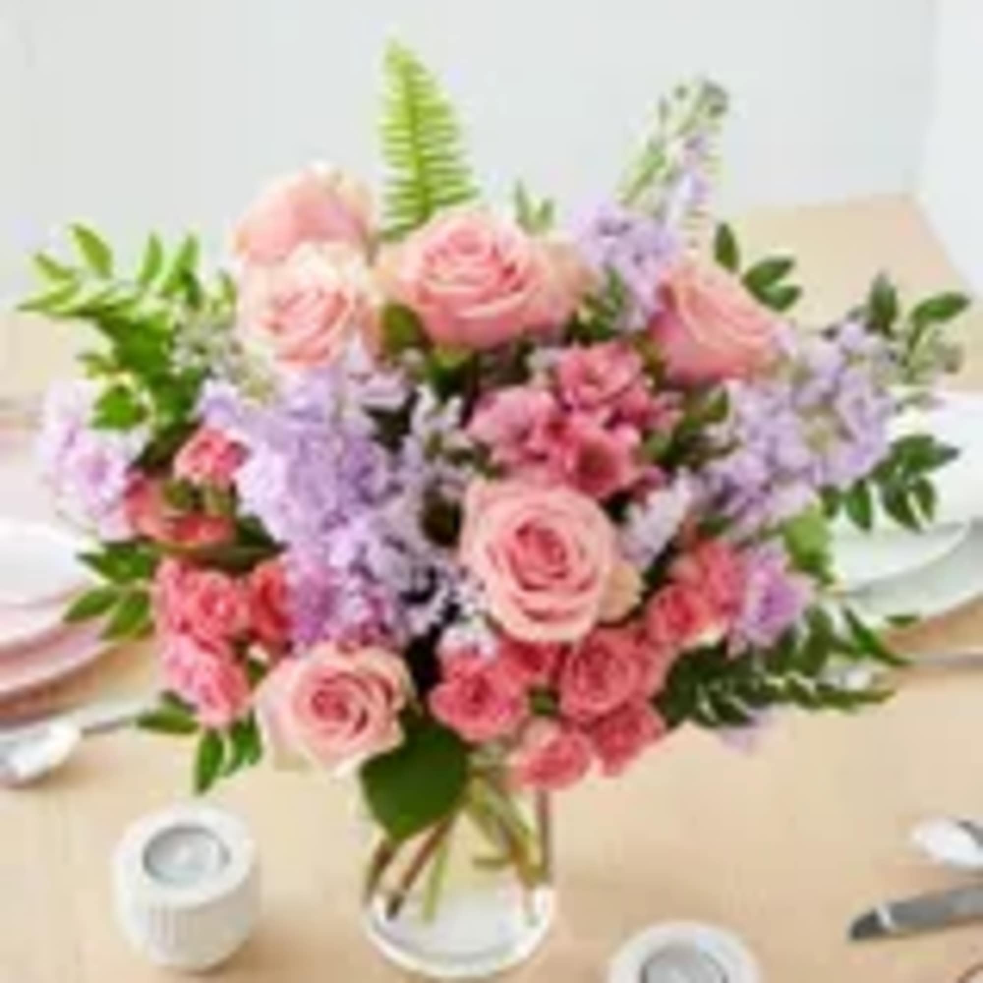 Pink roses and lavender flowers arranged in a clear glass vase