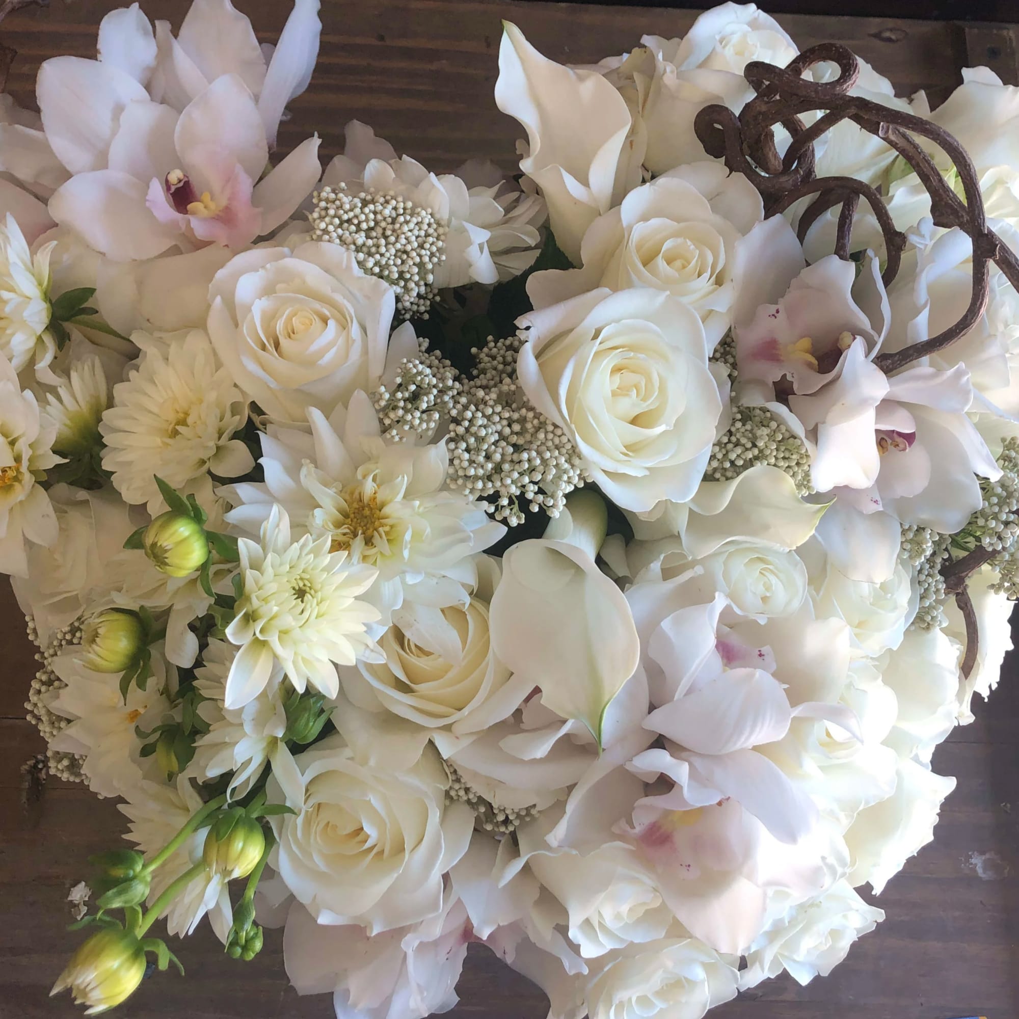 White roses, orchids, and daisies arranged in a heart shape