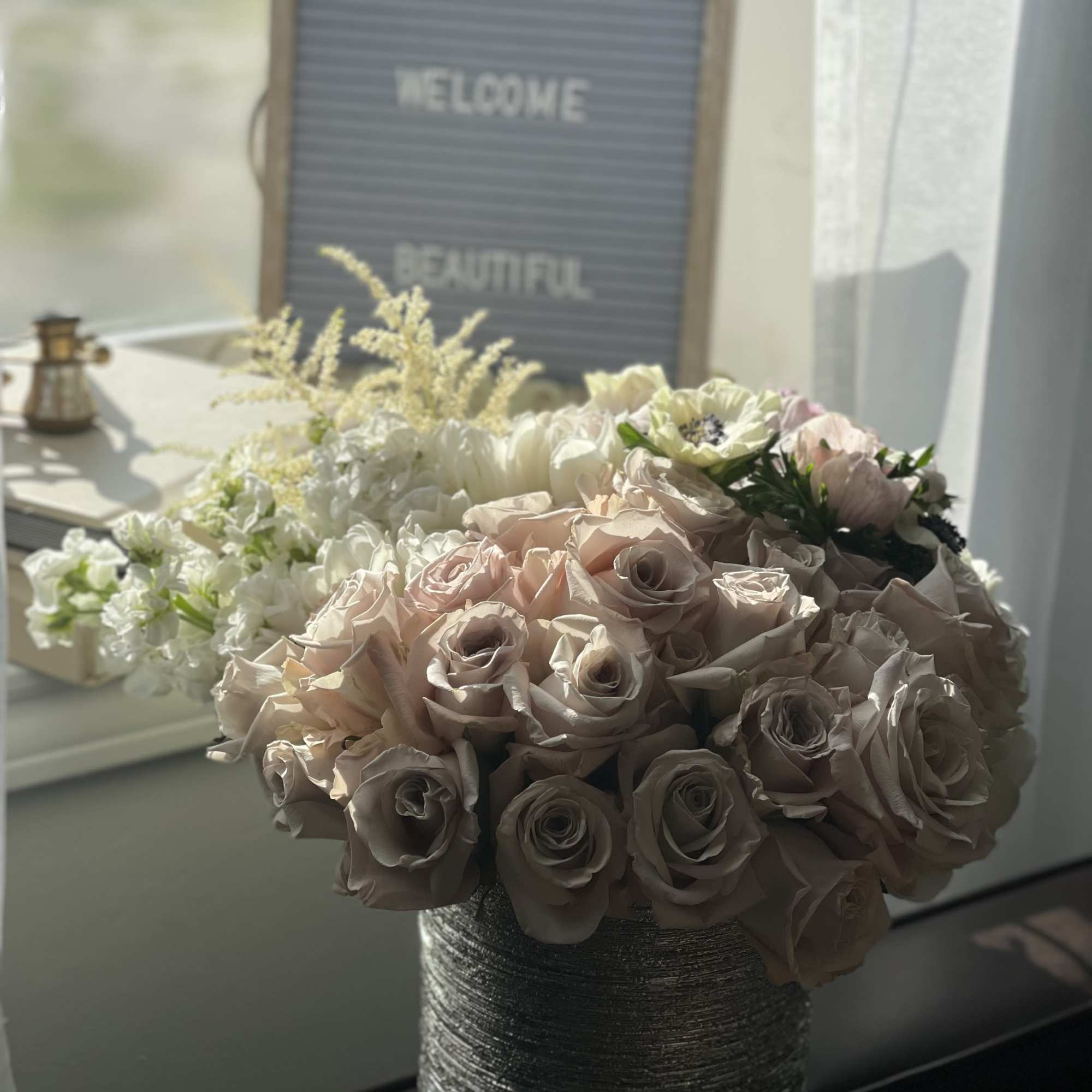 Bouquet of blush and white roses in a textured silver vase