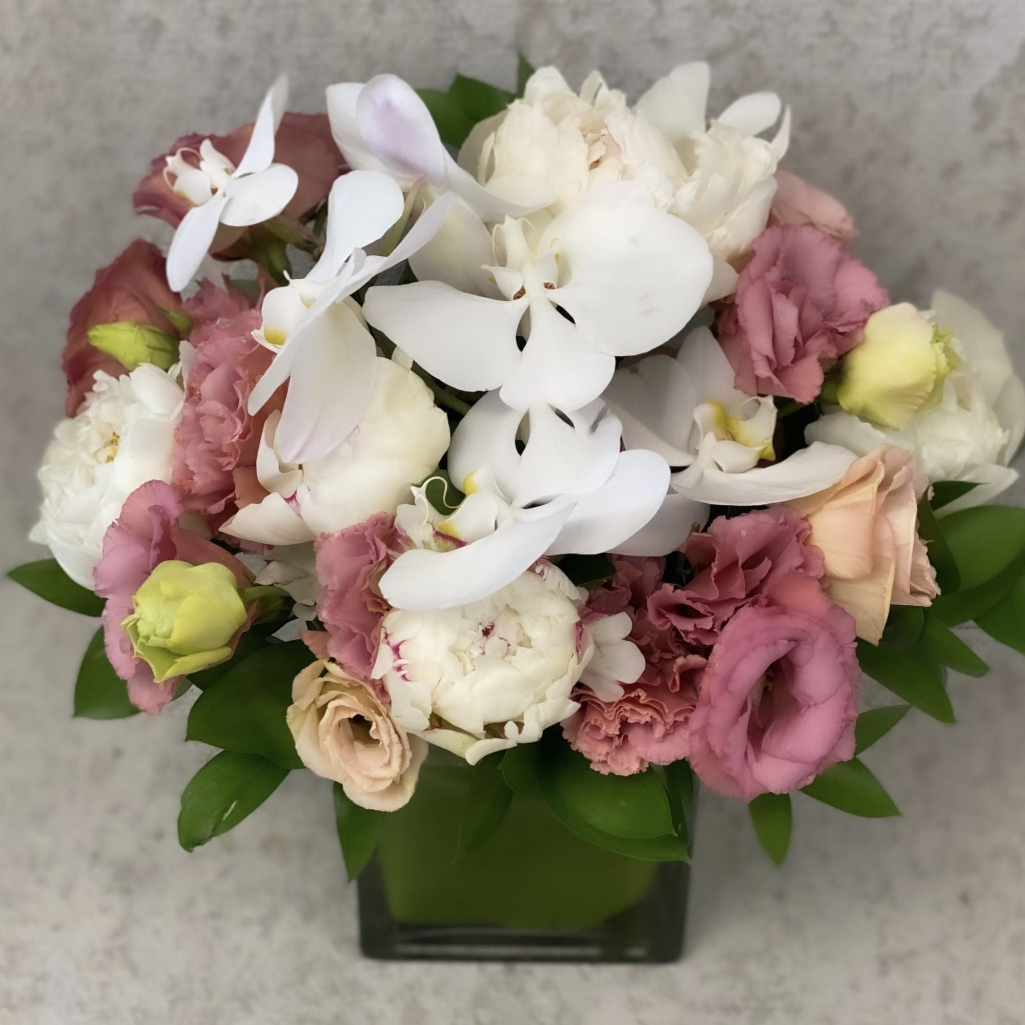 Bouquet of white orchids, pink roses, and carnations in a square vase
