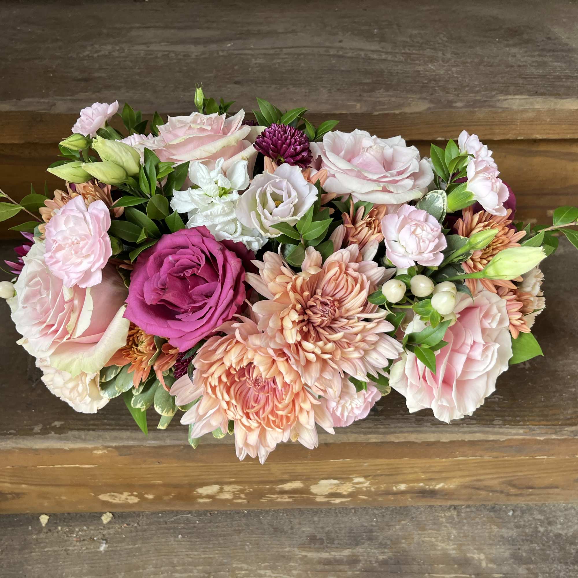 Low bouquet of pink and peach roses with chrysanthemums and greenery