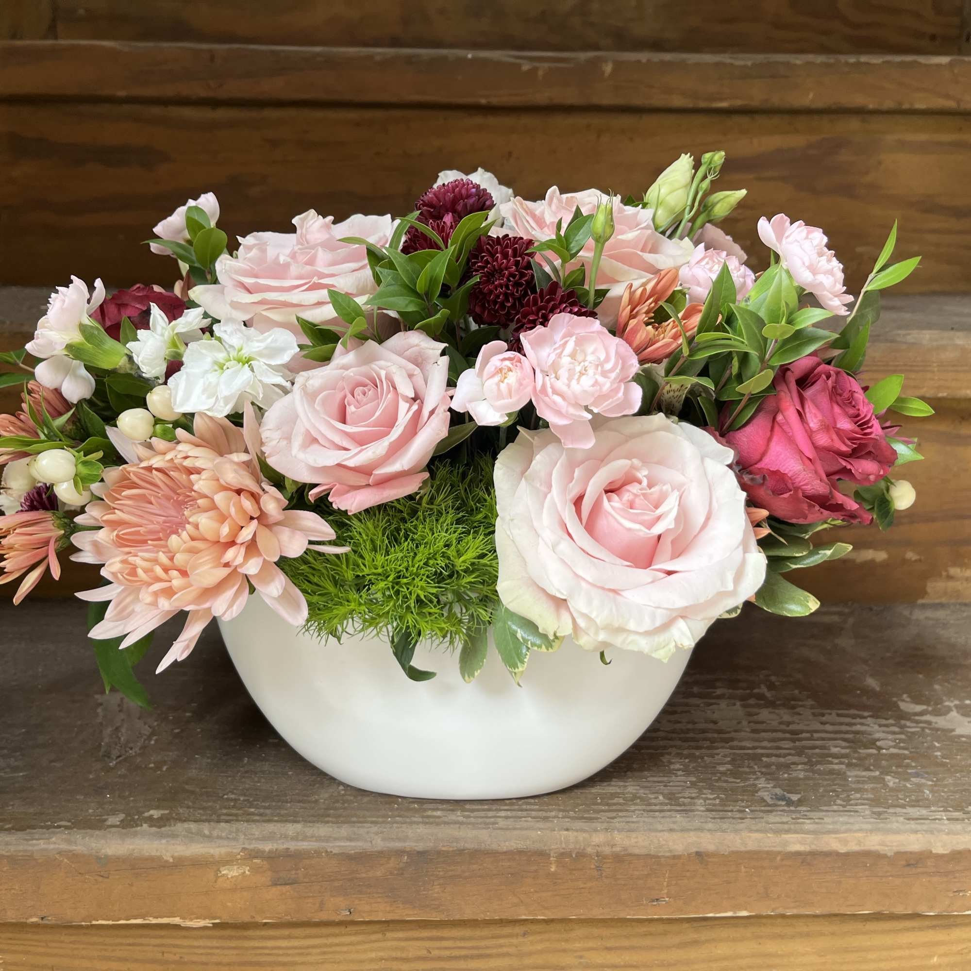 Pink and white mixed flower arrangement in a white bowl vase