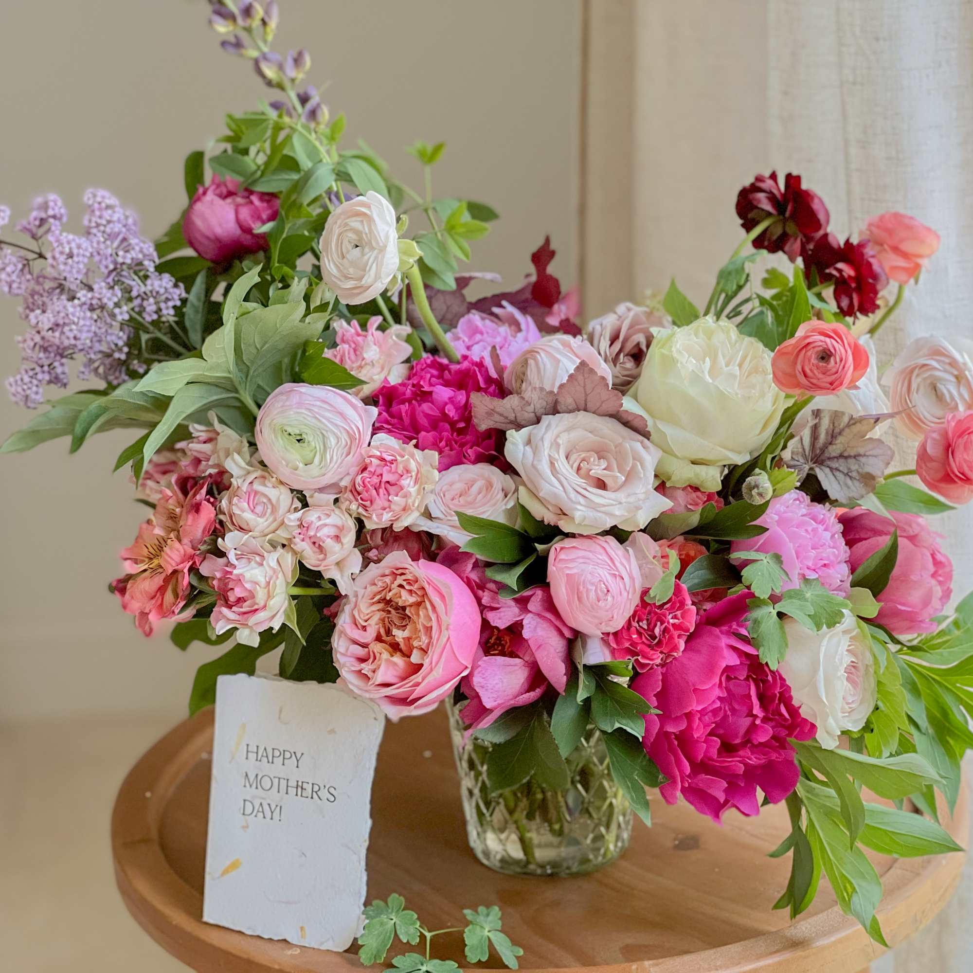 Mixed pink and white flower arrangement in a clear glass vase with a Mother's Day card