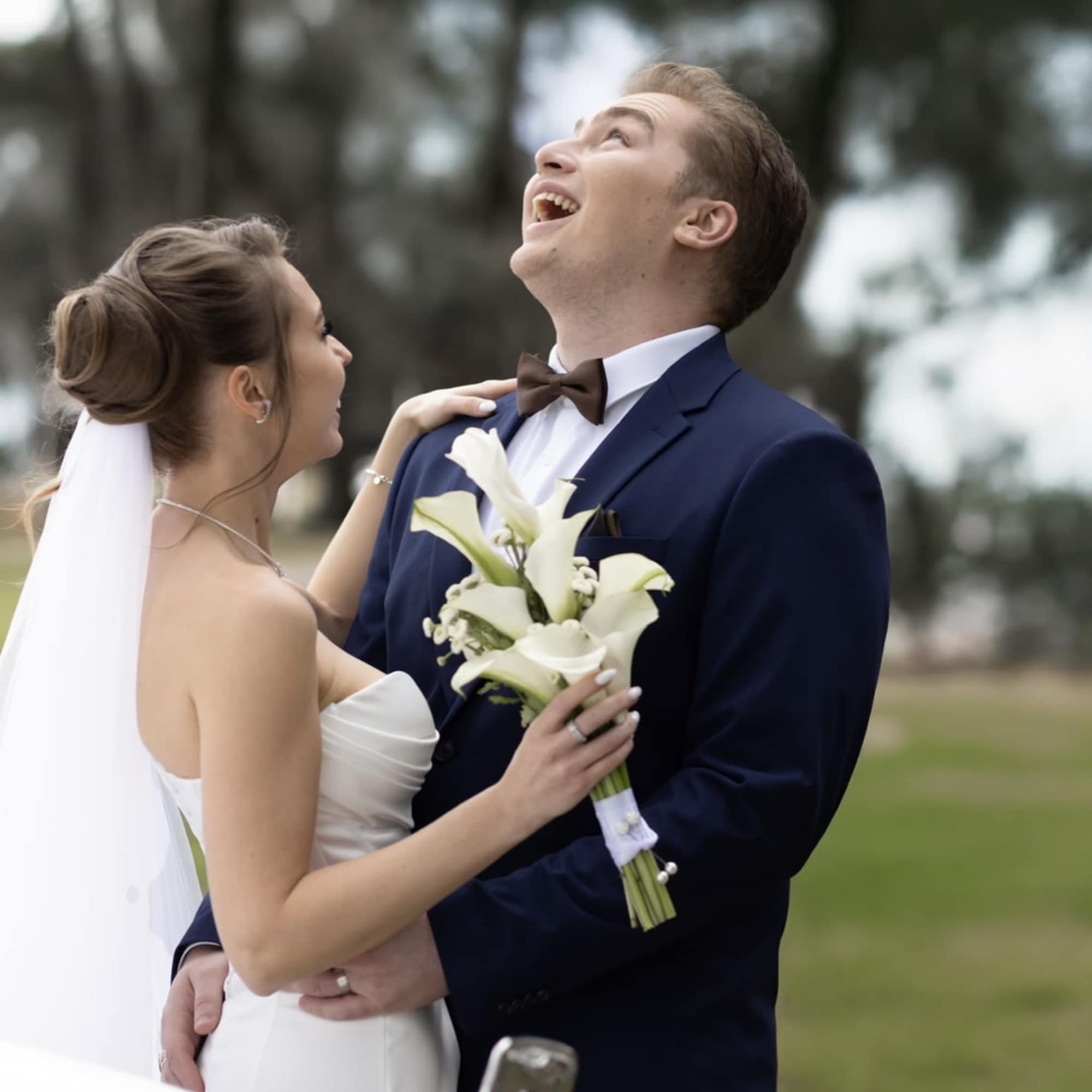 Bride holding a white calla lily bouquet with groom in a navy suit