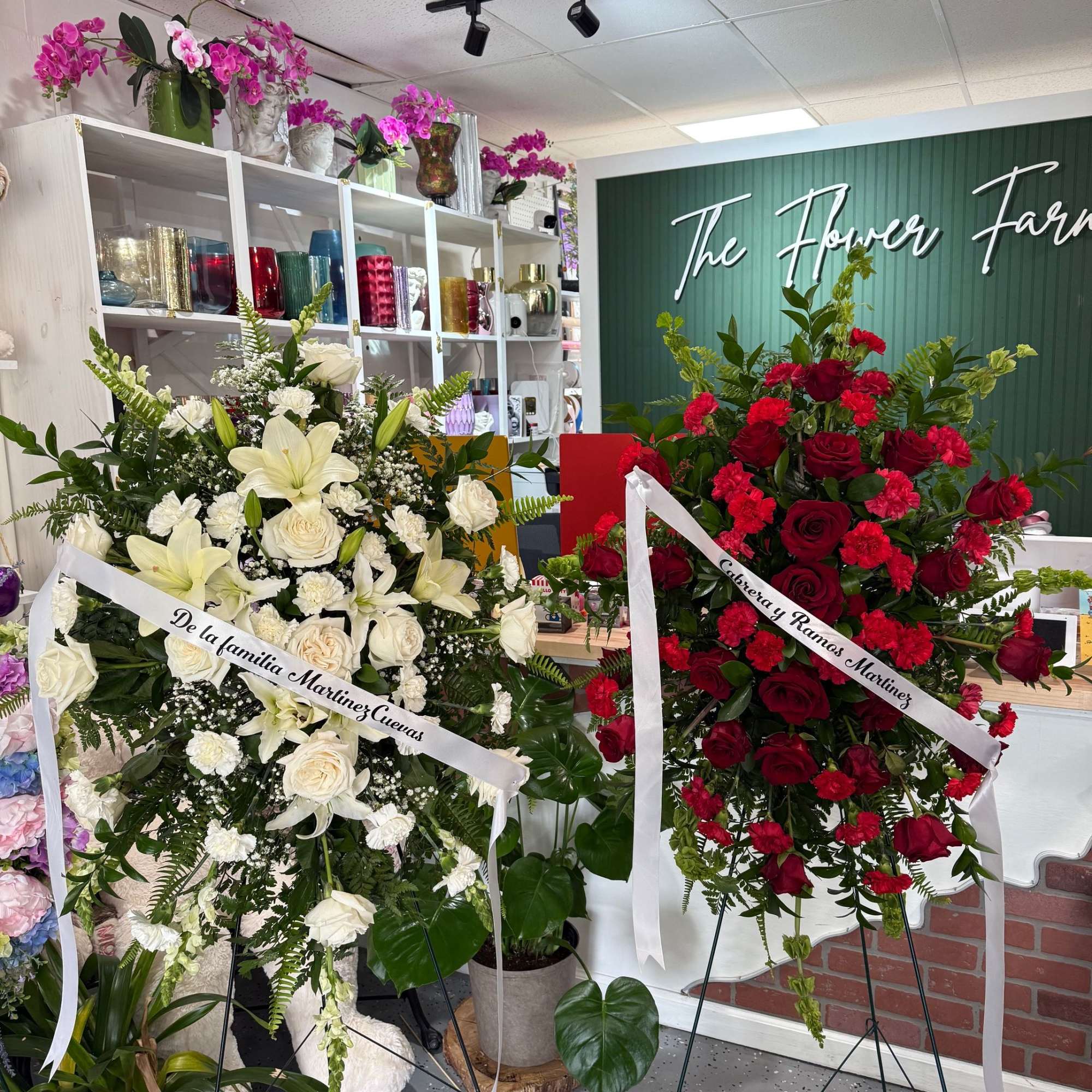Two standing funeral sprays, one white and one red, on easels with ribbons.