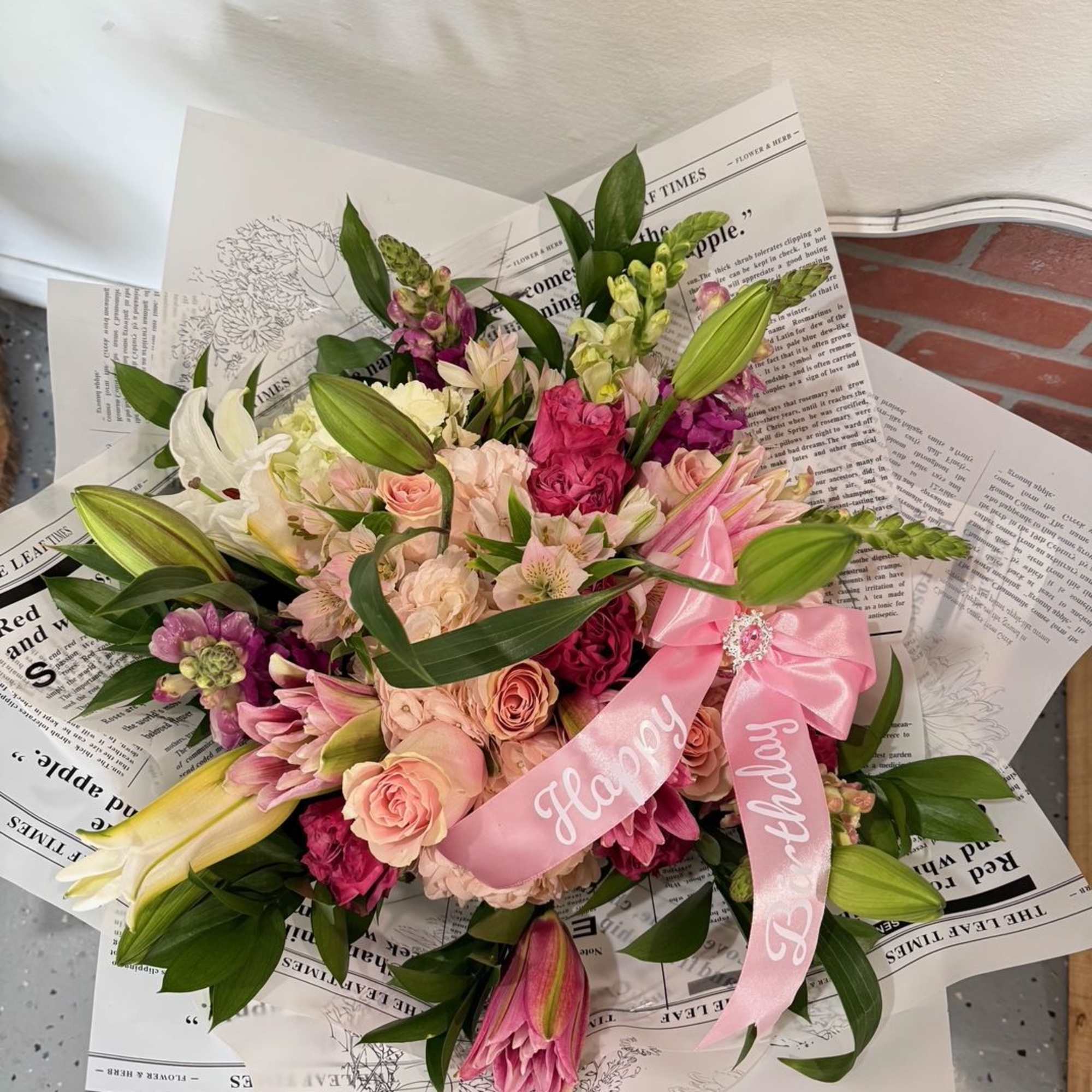 Pink and cream mixed bouquet with lilies and roses, tied with a pink ribbon