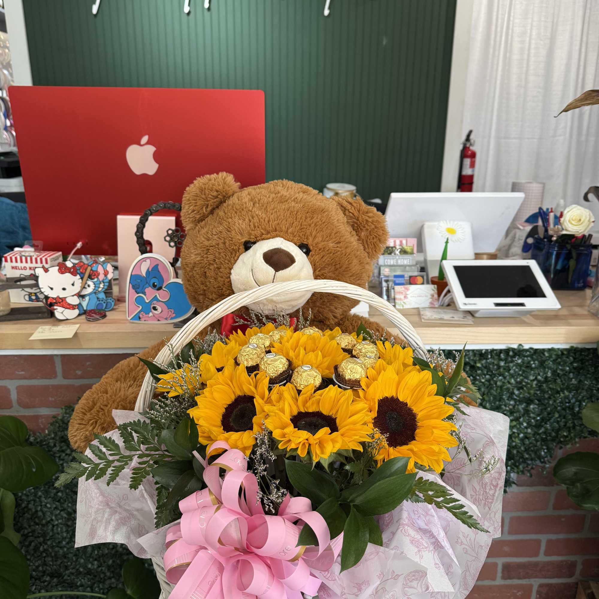 Basket of sunflowers with a teddy bear and pink ribbon