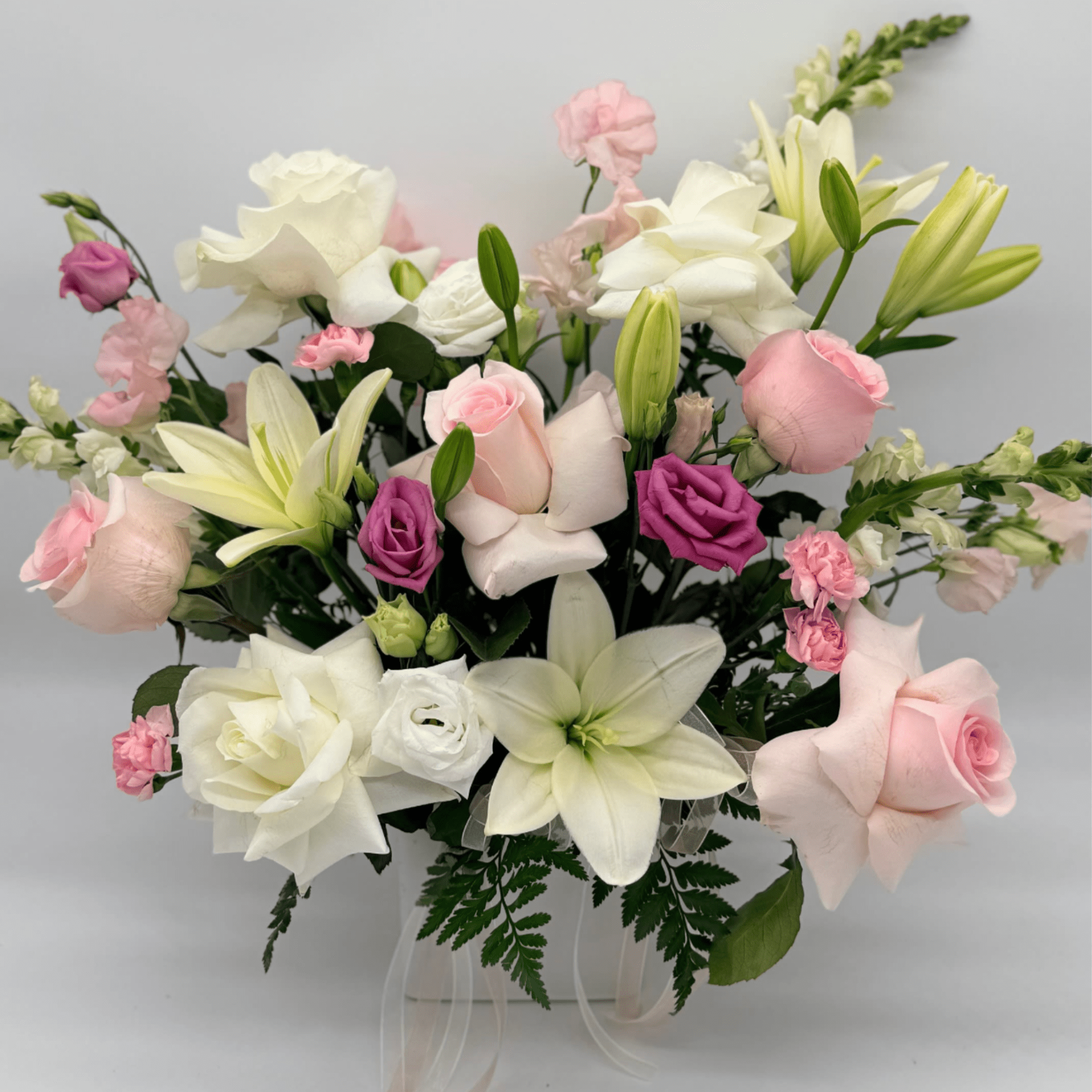 Bouquet of pink and white roses with lilies in a clear vase