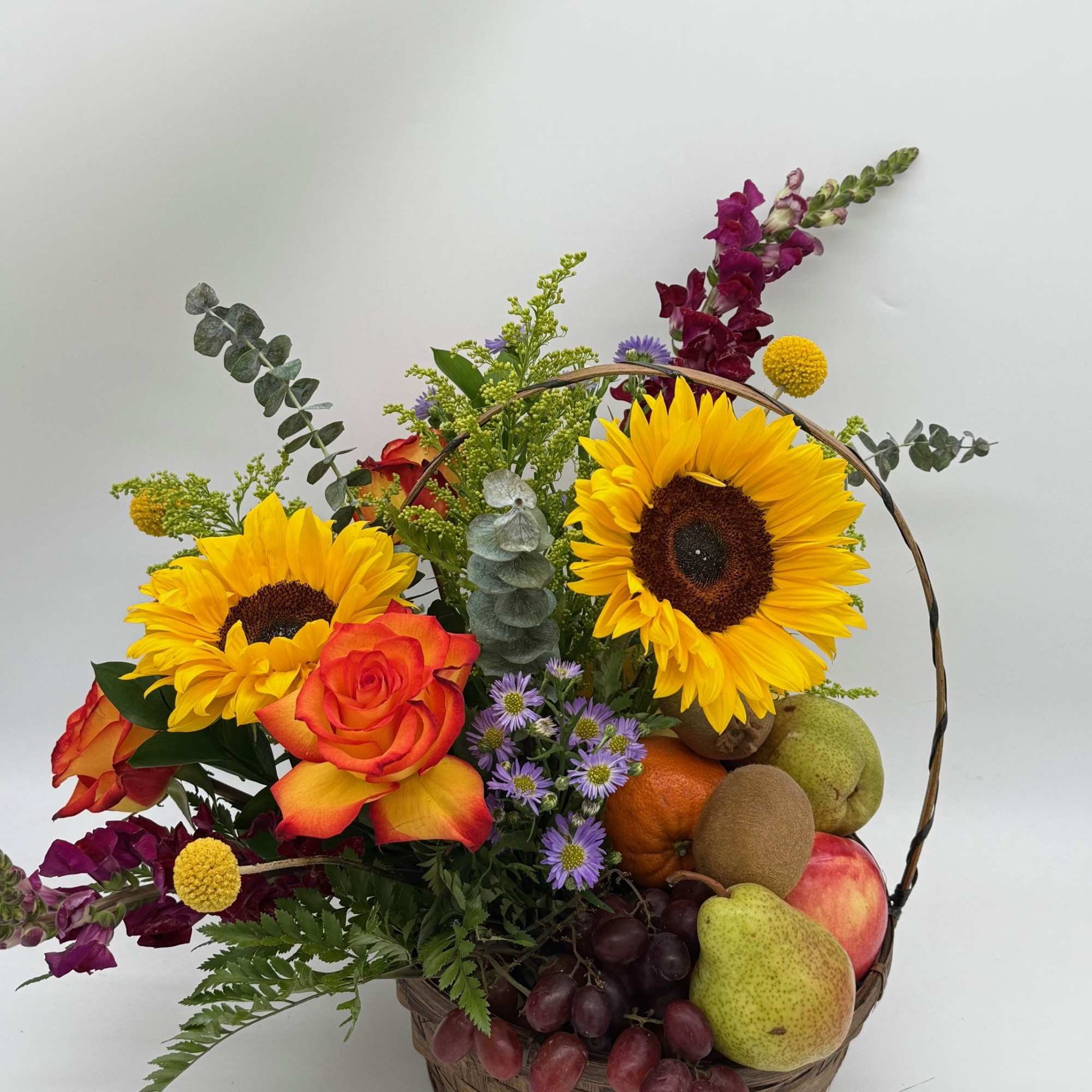 Basket arrangement with sunflowers, roses, grapes, and assorted fruit
