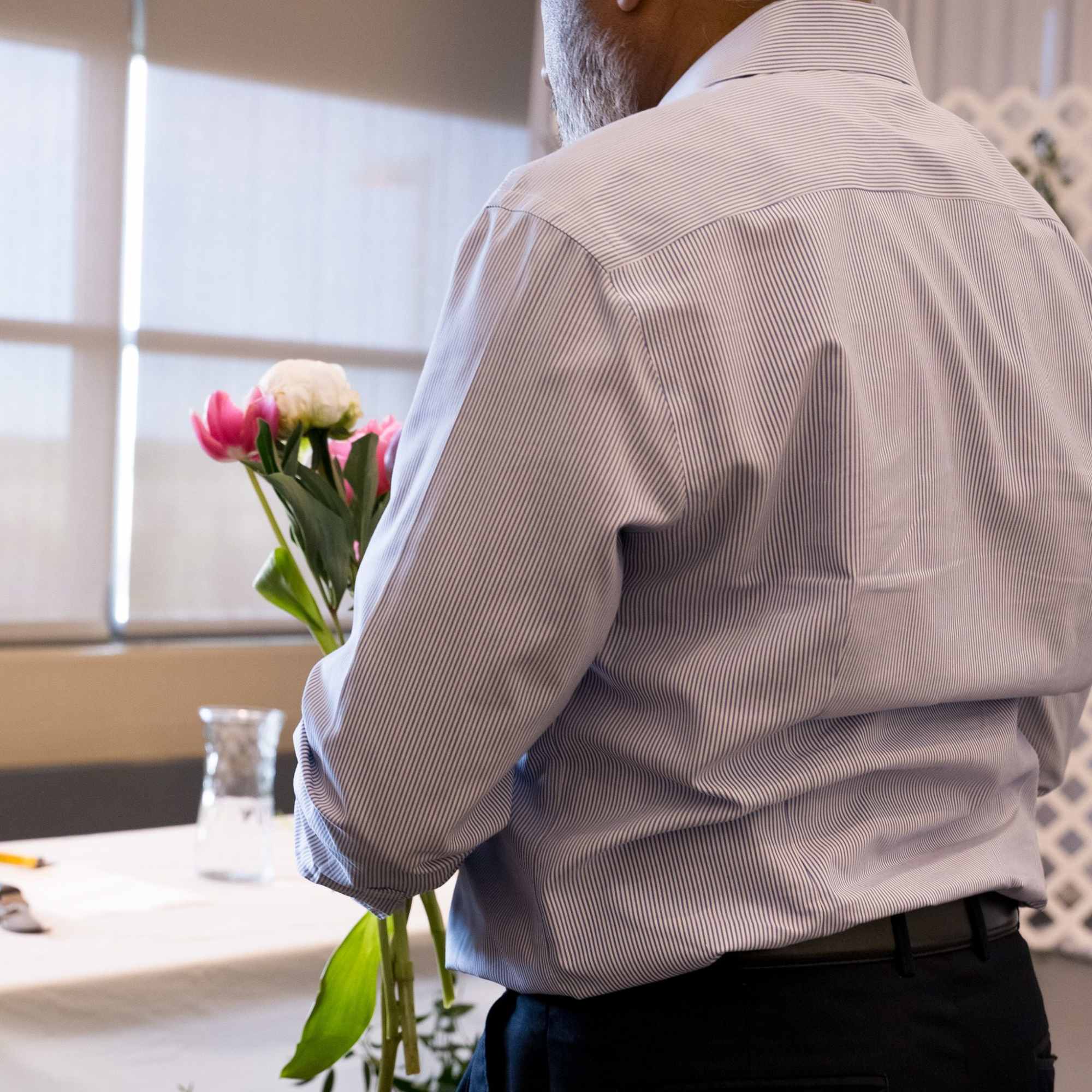 Person holding a small bouquet of pink and white flowers