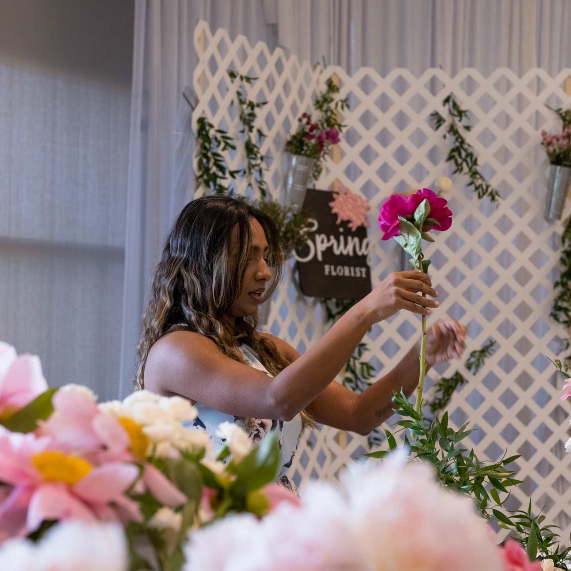 Woman arranging a pink flower on a lattice floral display
