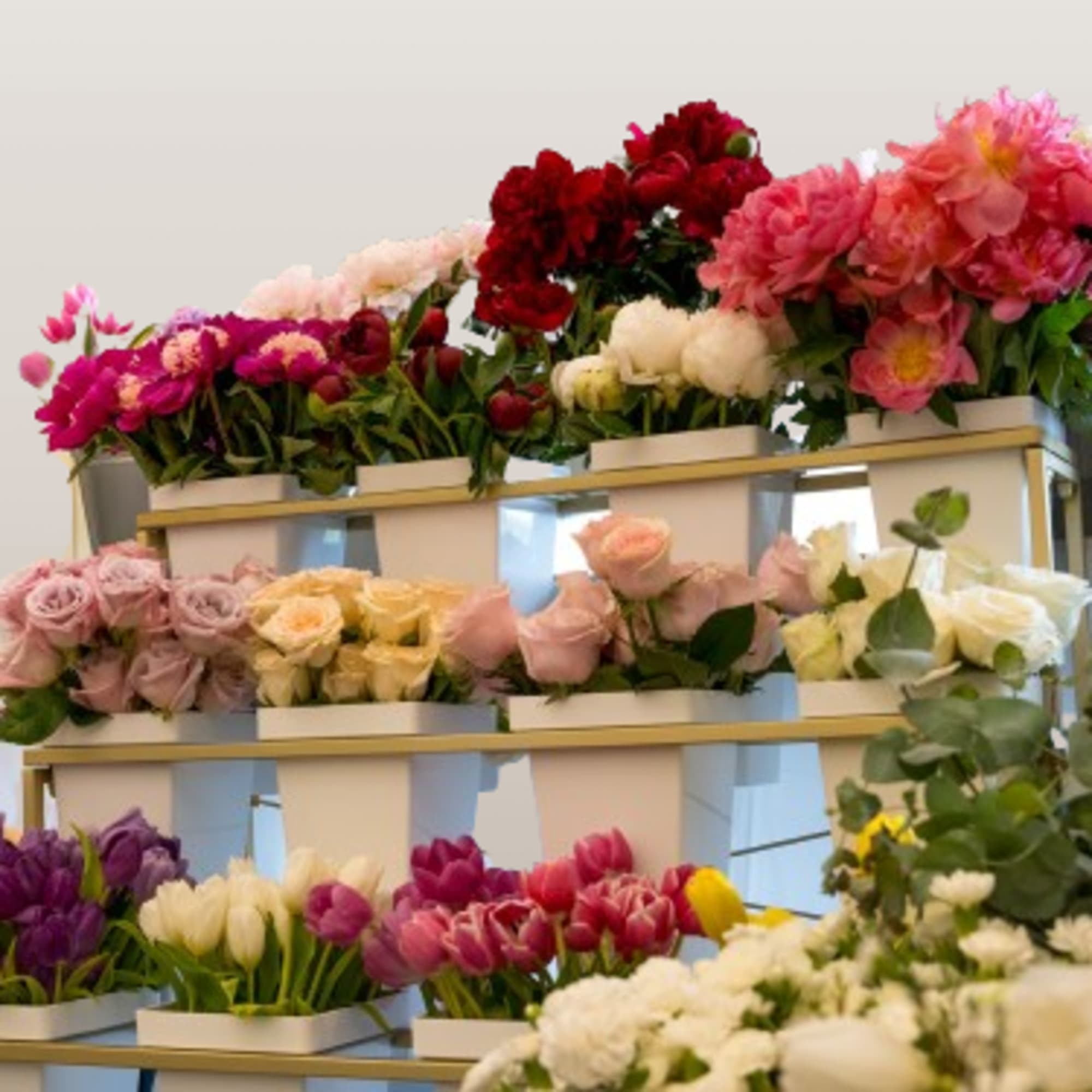 Tiered display of assorted bouquets in white boxes with pink, red, white, and purple flowers