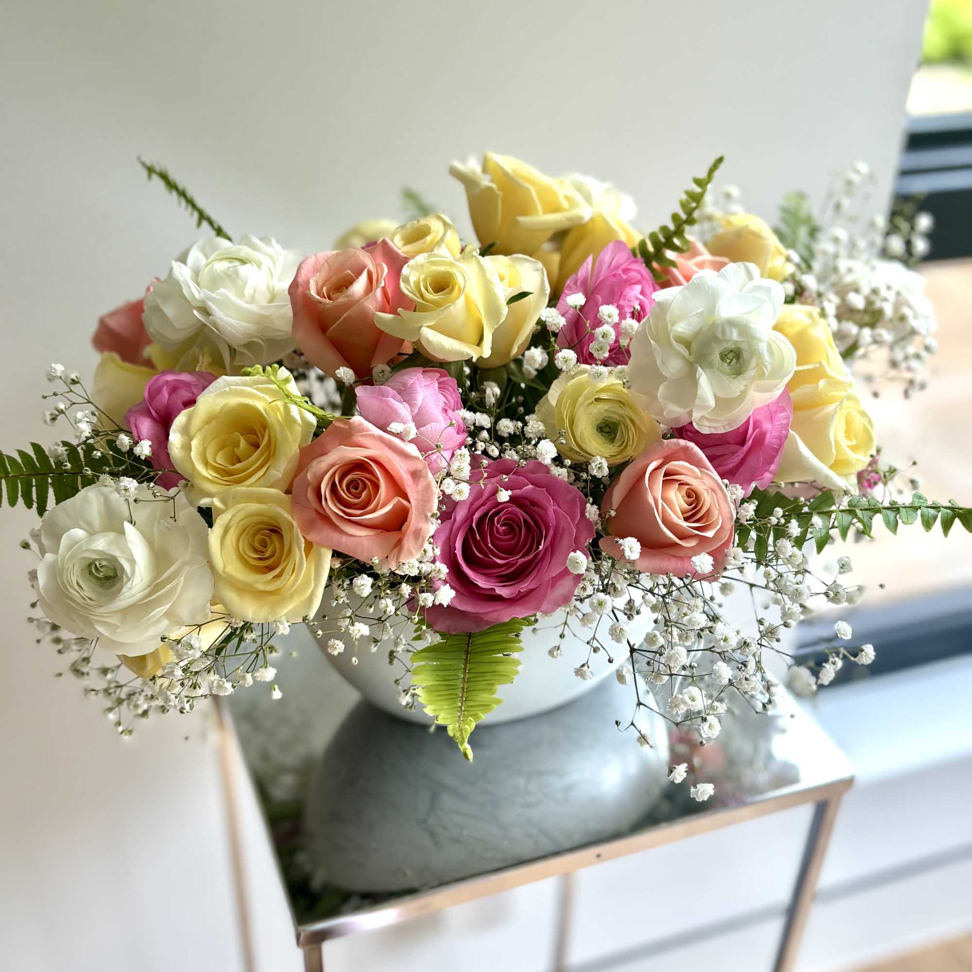 Mixed roses in pink, yellow, peach, and white arranged in a vase