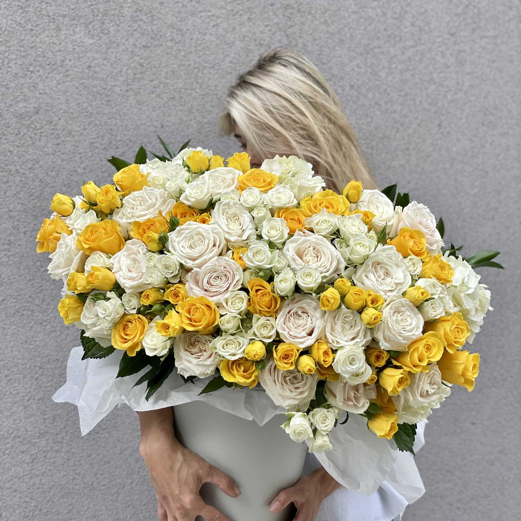 Large bouquet of yellow and white roses in a white container