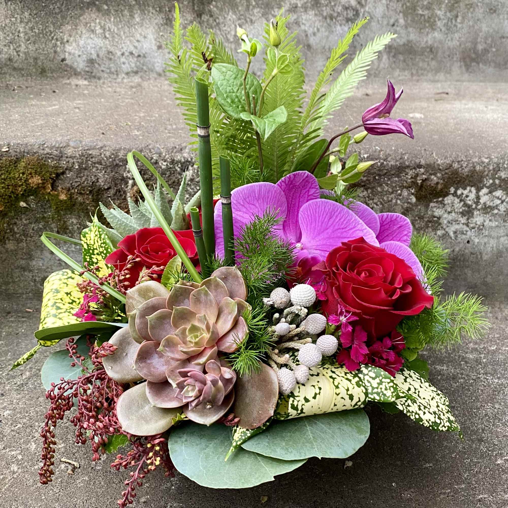 Mixed bouquet with red roses, purple orchids, and succulents