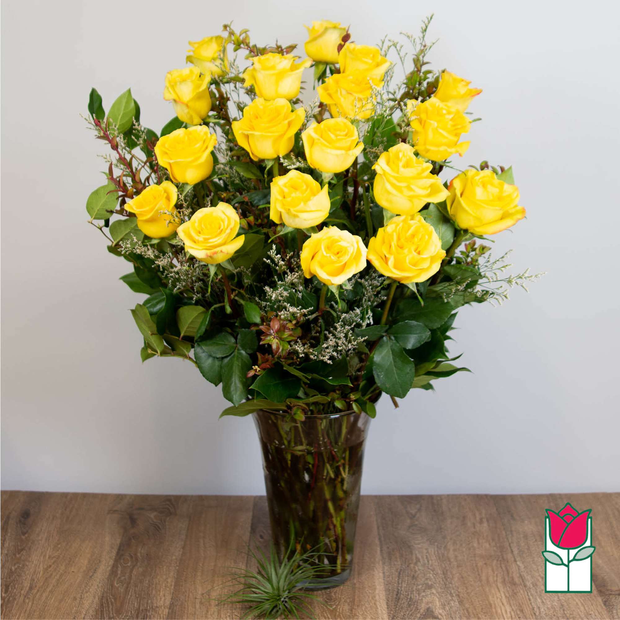 Yellow roses arranged in a tall glass vase