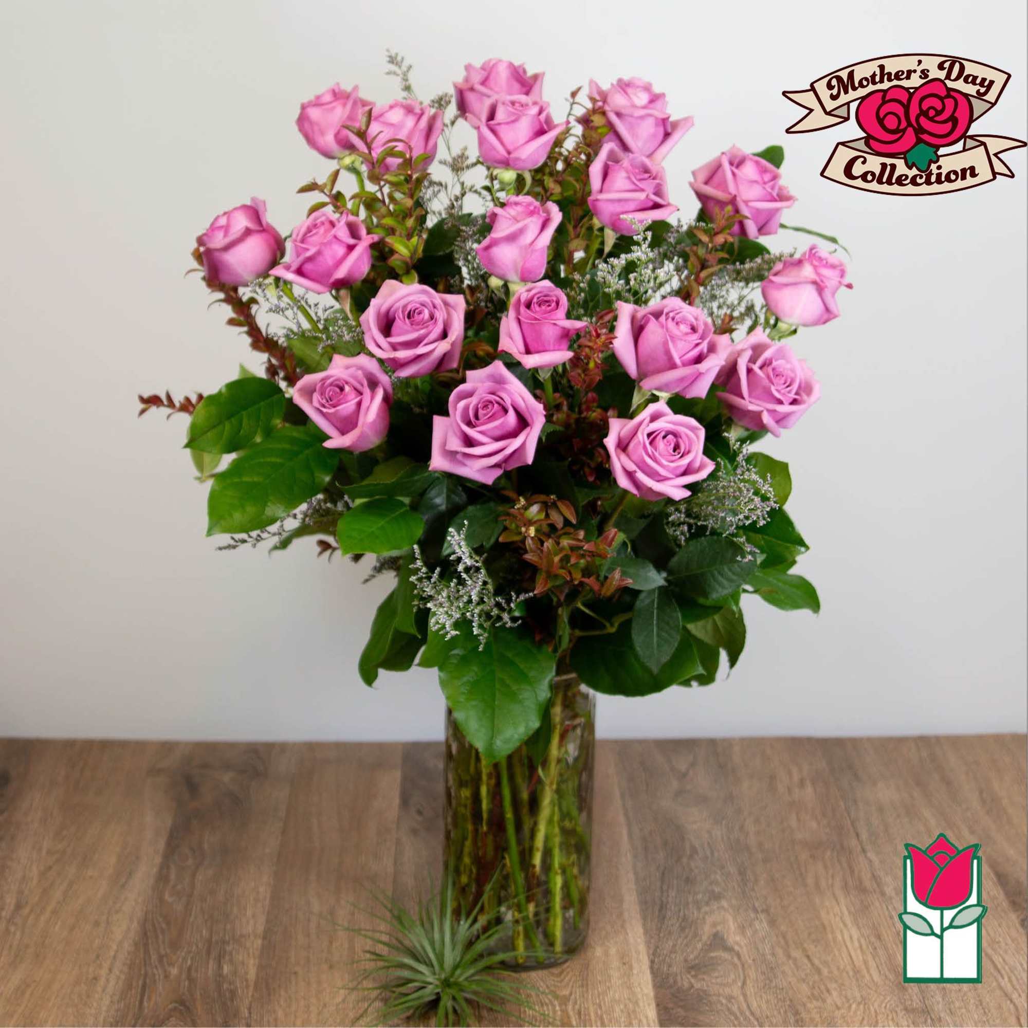 Pink roses arranged in a tall glass vase with greenery.