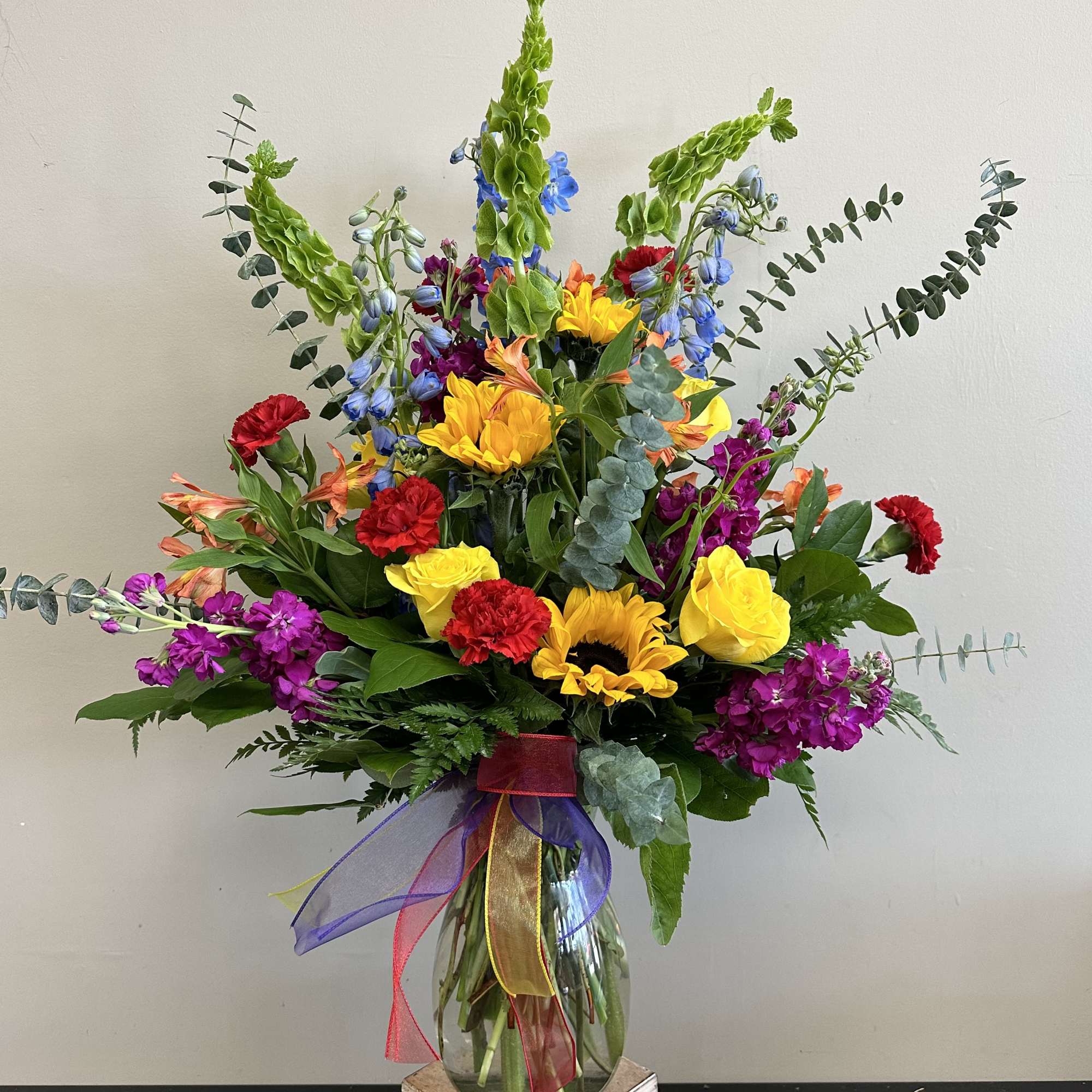 The perfect bright floral arrangement filled with sunflowers, stock, larkspur, alstroemeria and